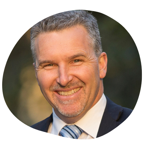 A smiling man with grey hair and a blue tie.