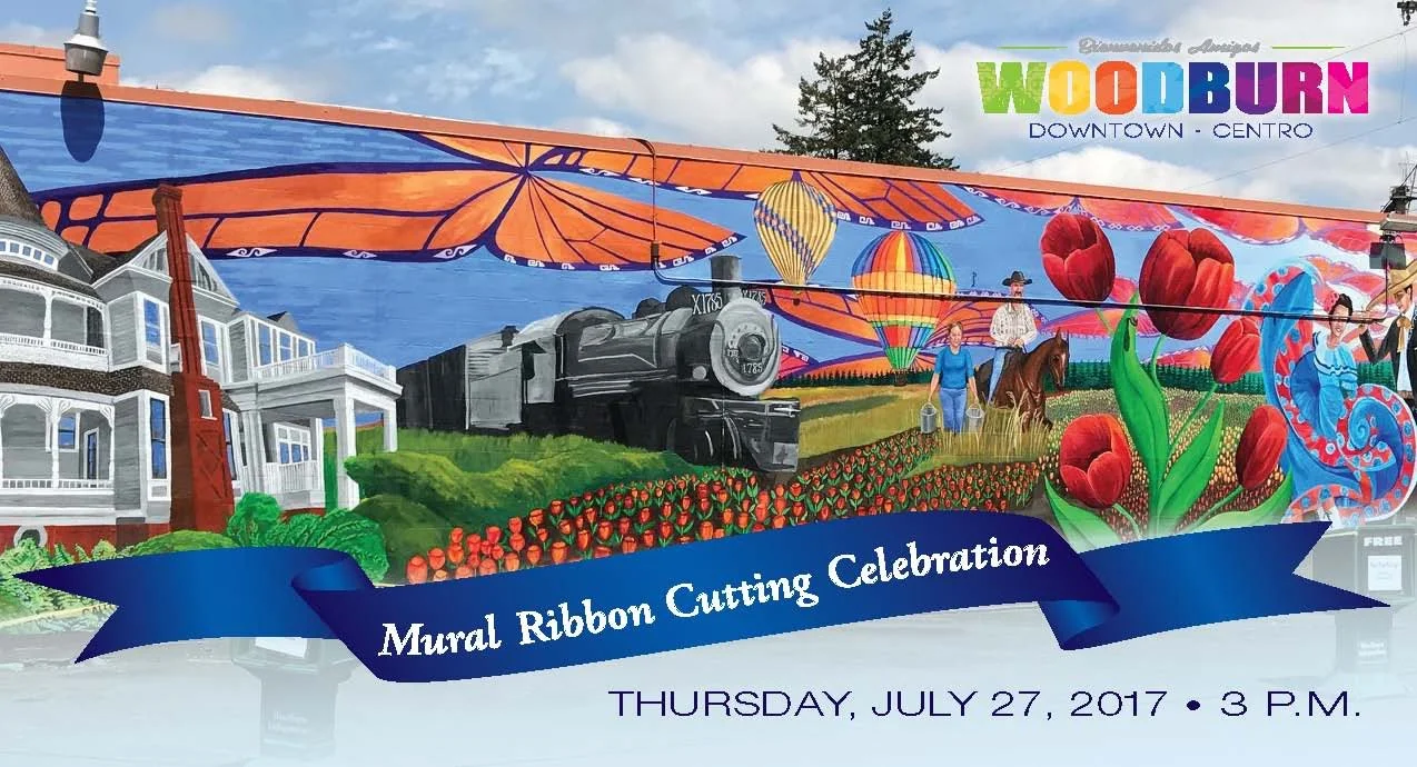 Colorful mural celebrating the Woodburn Downtown Mural Ribbon Cutting Event on July 27, 2017, featuring a train, hot air balloons, large flowers, two people with a horse, and a historic house.