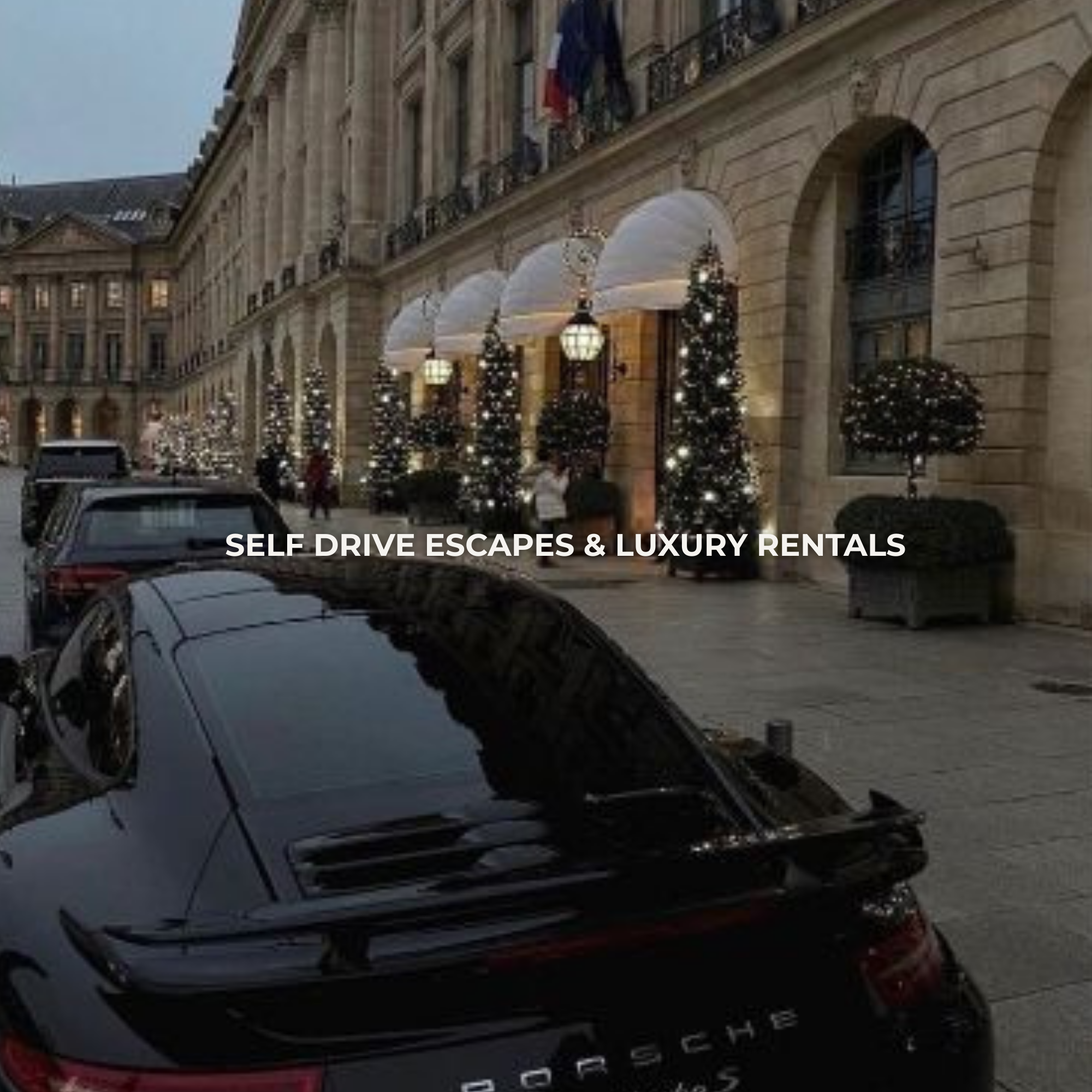 Luxury street scene with a black Porsche parked in front of a historic building decorated with Christmas lights and potted trees.