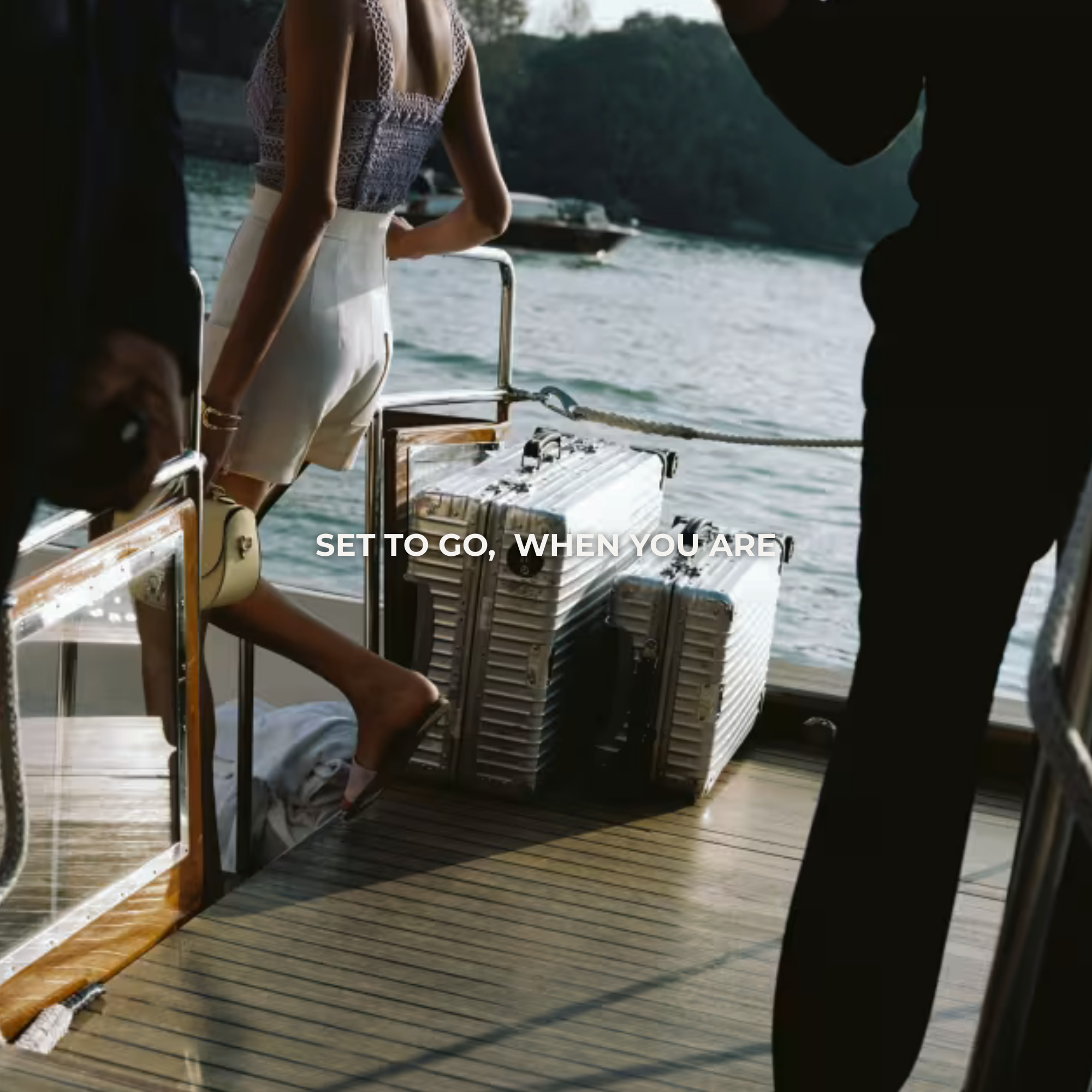 Two silver hard shell suitcases with a Louis Vuitton duffle bag on top, at an airport entrance.