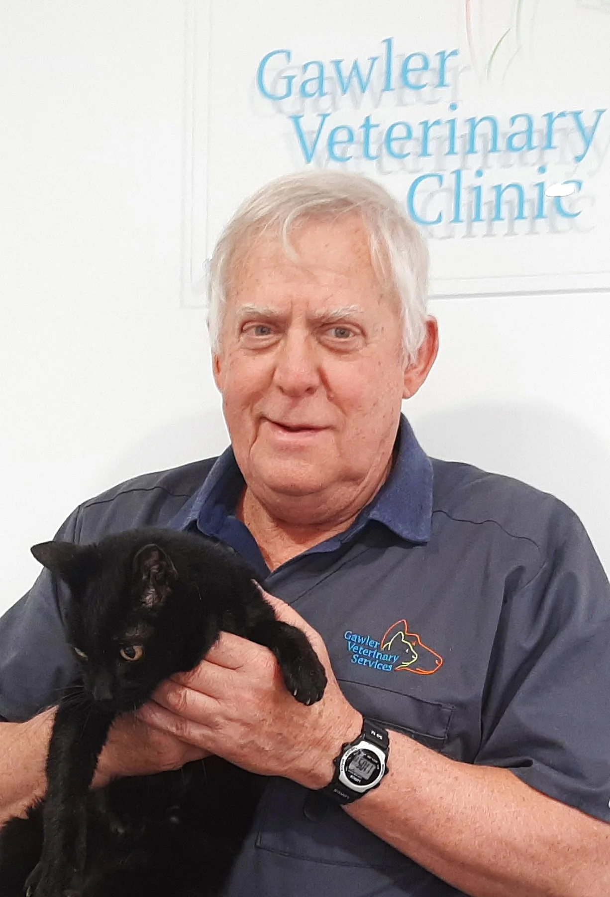 Smiling woman with curly hair, wearing glasses, hoop earrings, layered necklaces, and a striped top.