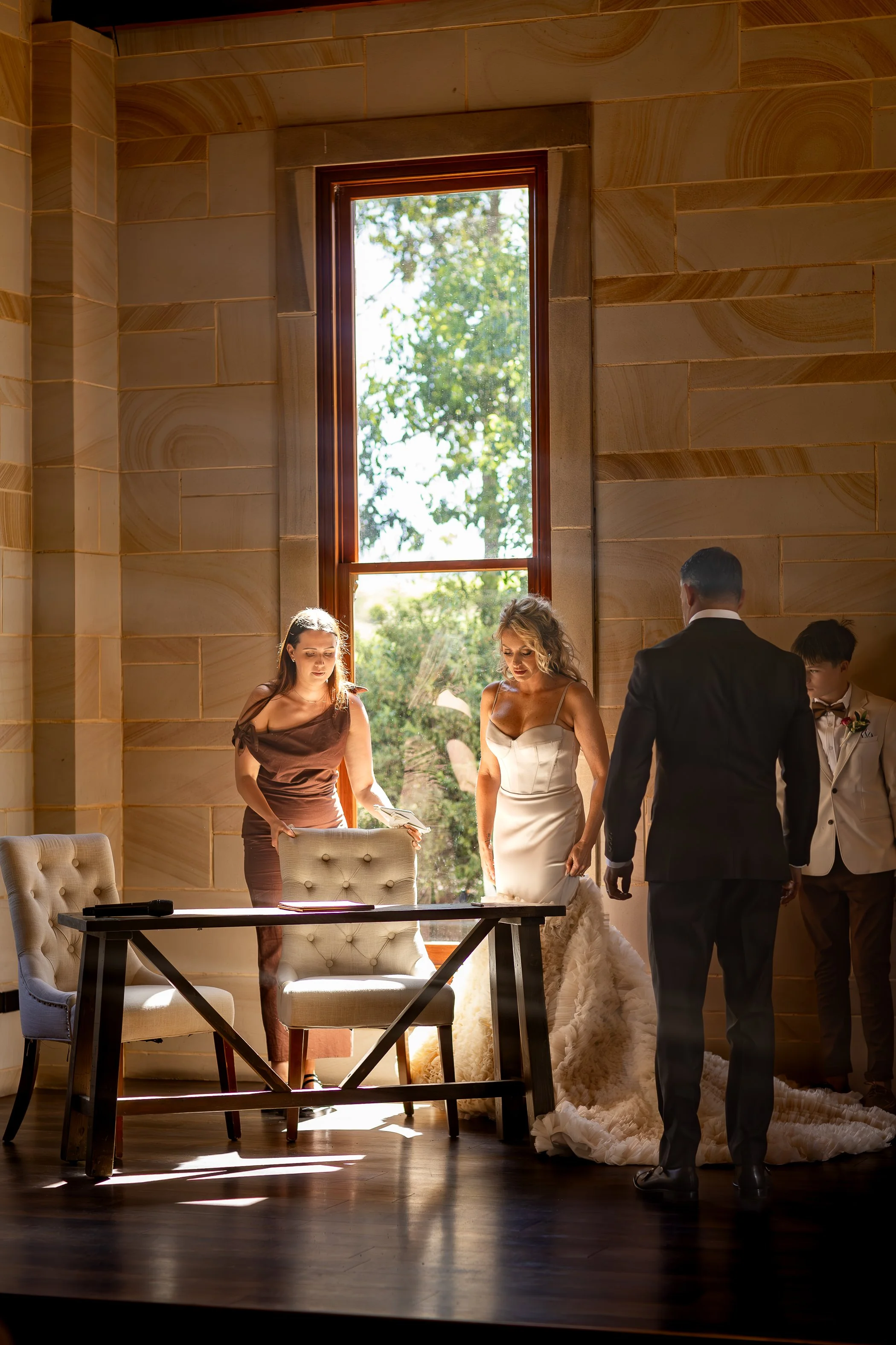 A bride and groom with two attendants in a sunlit room, preparing for their wedding WITH a NEWCASTLE AND HUNTER VALLEY WEDDING CELEBRANT