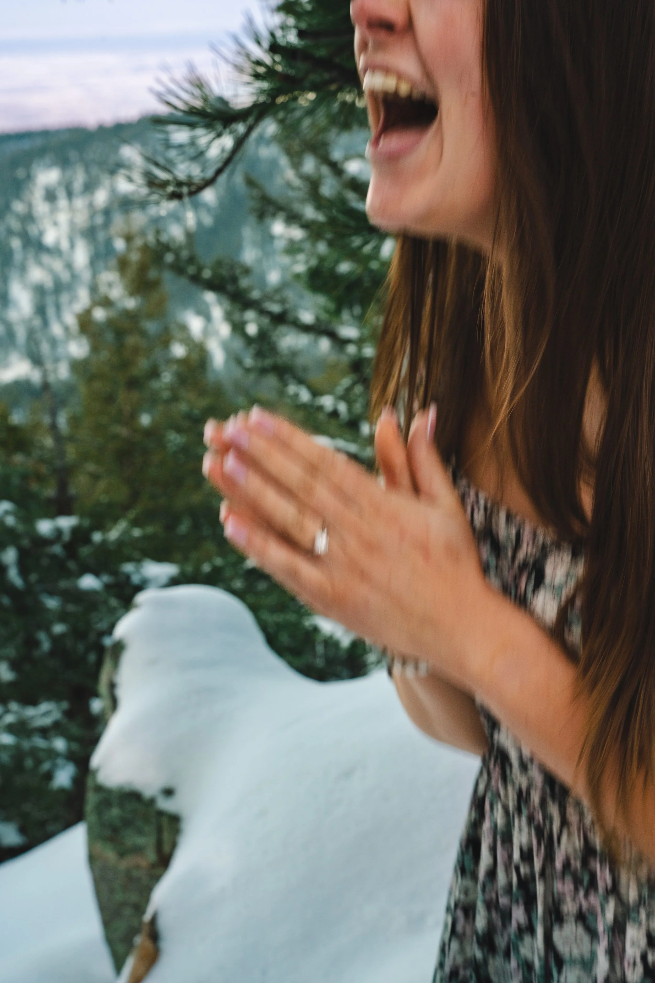 A candid moment after a lady said yes to her fiancés proposal.  It is blurry but the emotion is captured.  It is cropped in on her smile and her hands clasped together while she is jumping from excitement.
