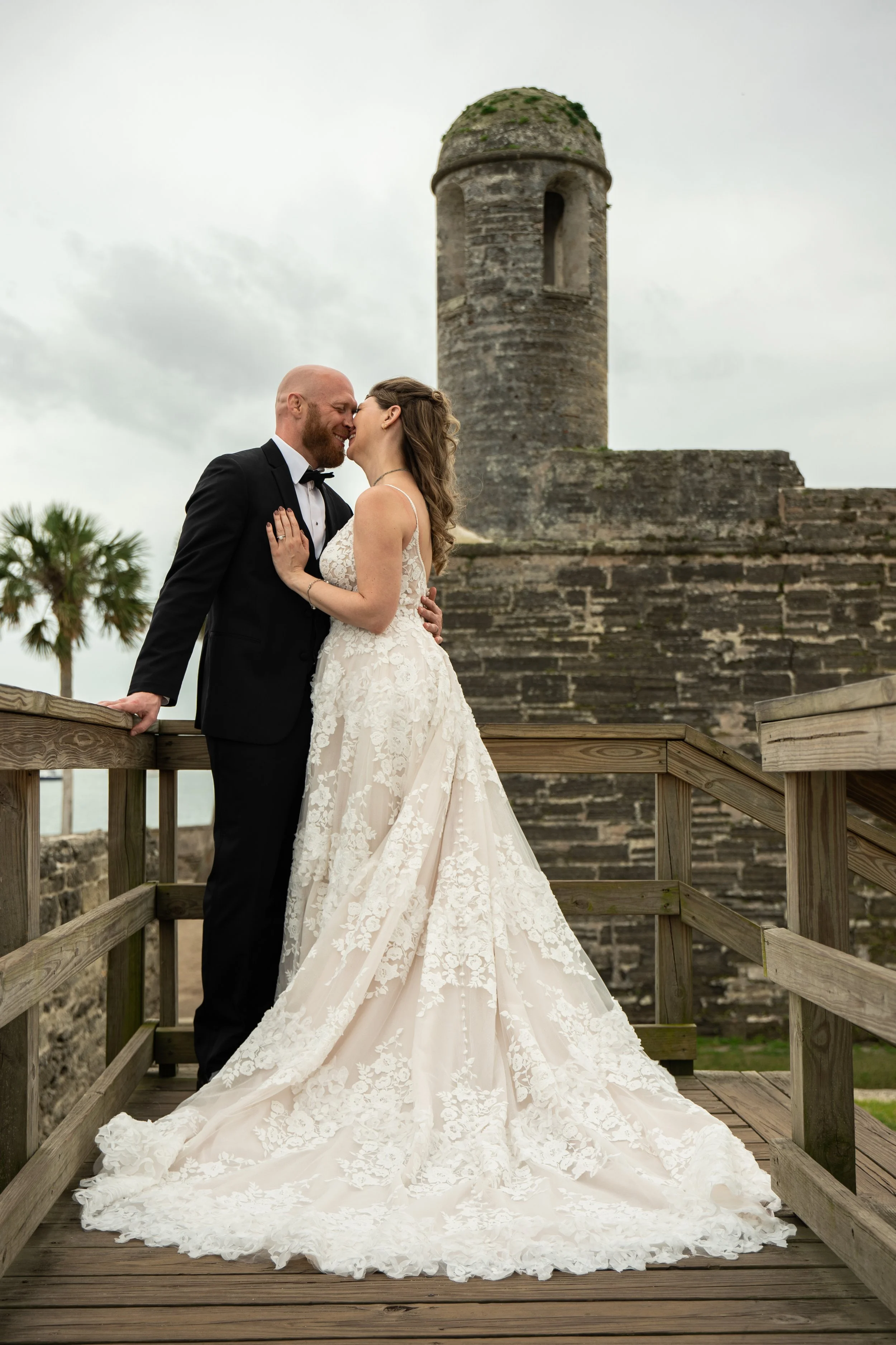 An elopement at an old castle in St. Augustine, FL.  A couple is embraced, both mid laugh from a joke one of them said.  They are lost in a moment together, surrounded by beautiful scenery.