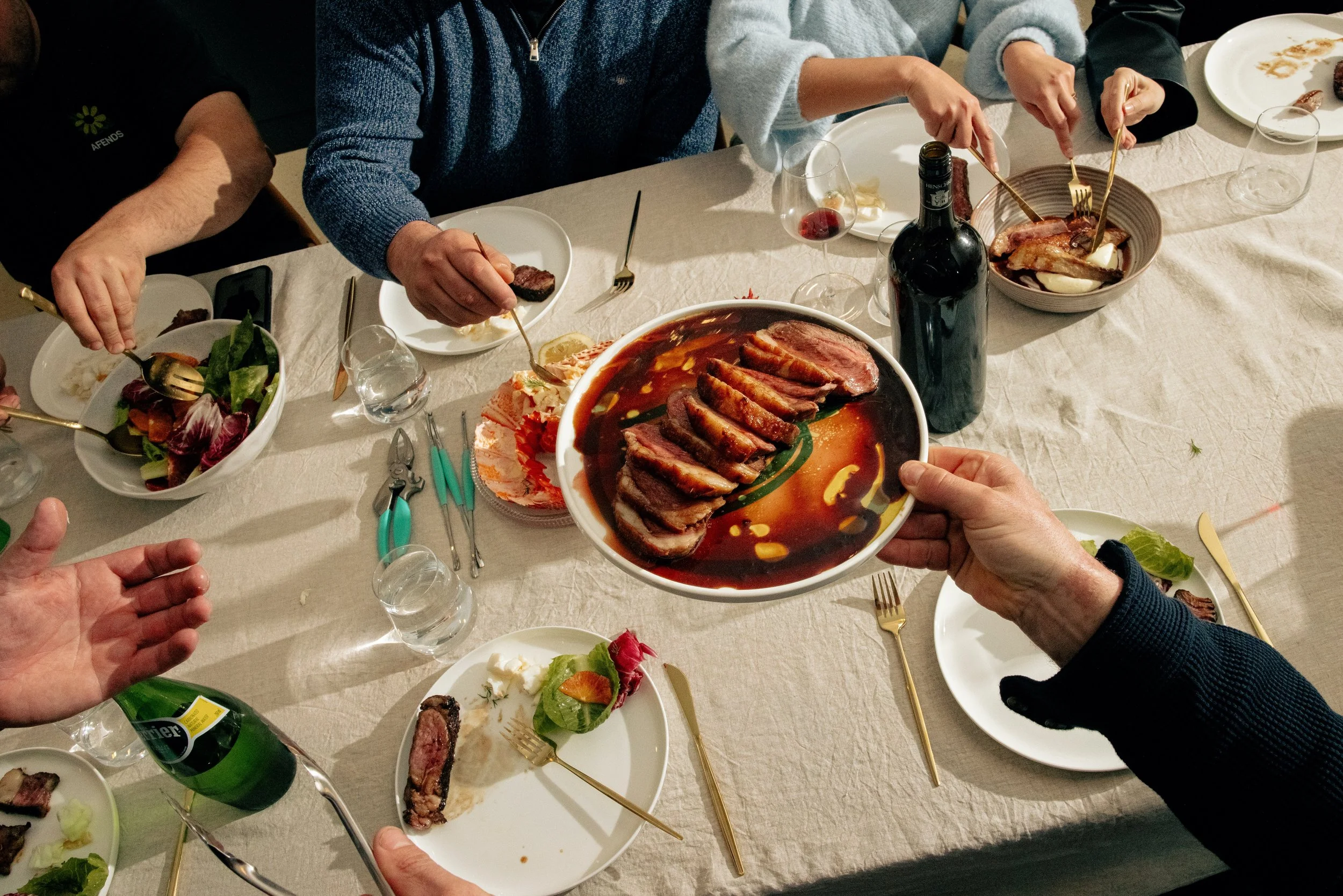 People gathered around a dinner table sharing a meal prepared by the best private chef in Adelaide.