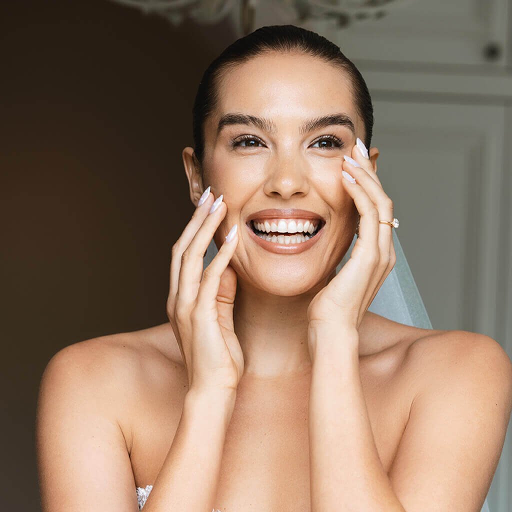 Smiling woman wearing a bridal veil, representing personalised skin preparation and skin-health planning before a wedding.
