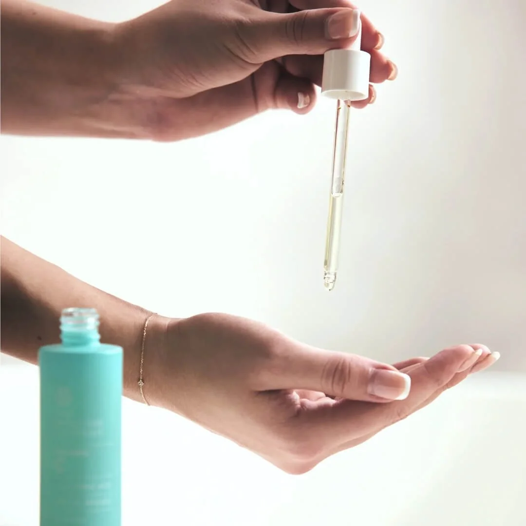 Vitamin C Serum being dispensed from a dropper onto a hand.