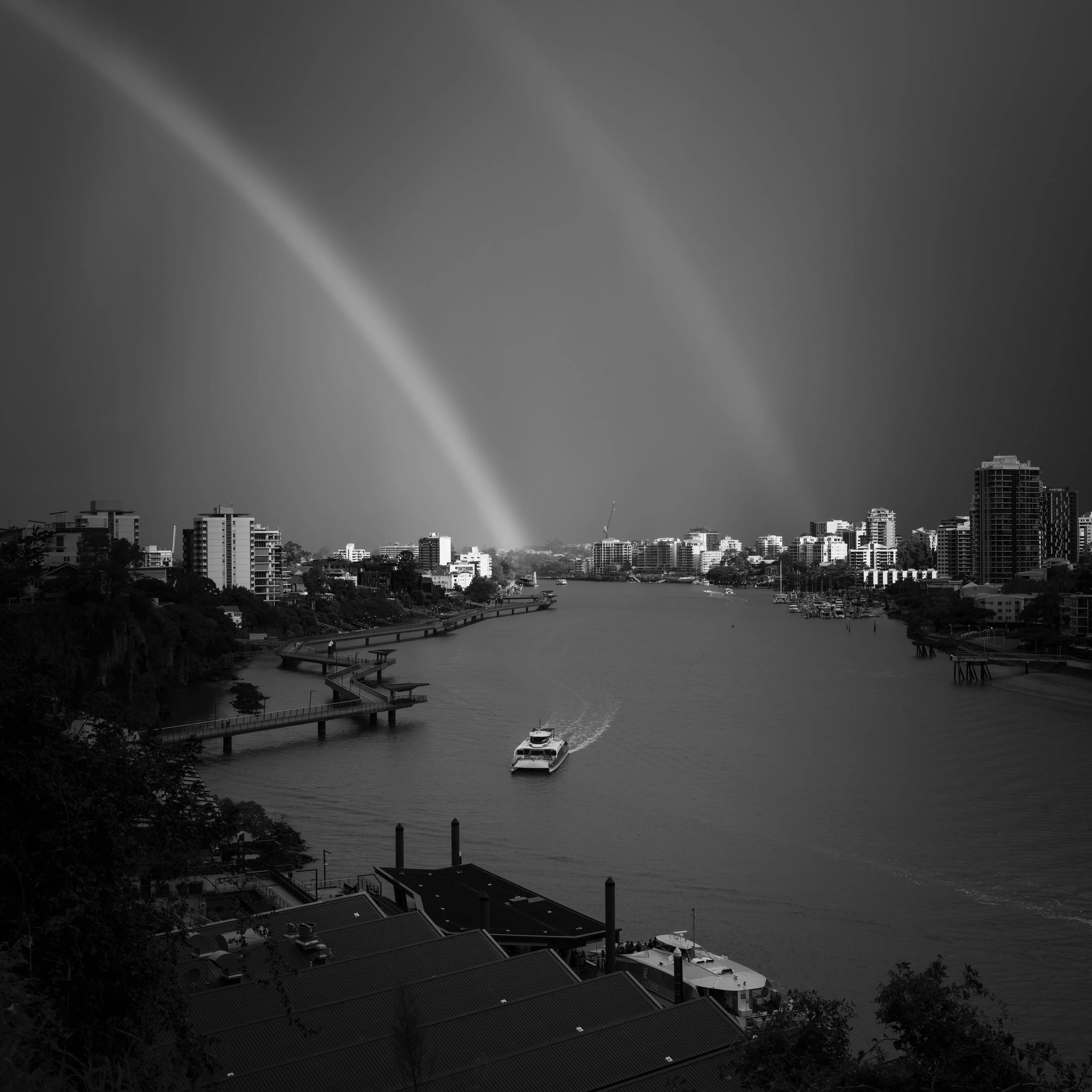 Black and white photo of Brisbane's cityscape with a double rainbow