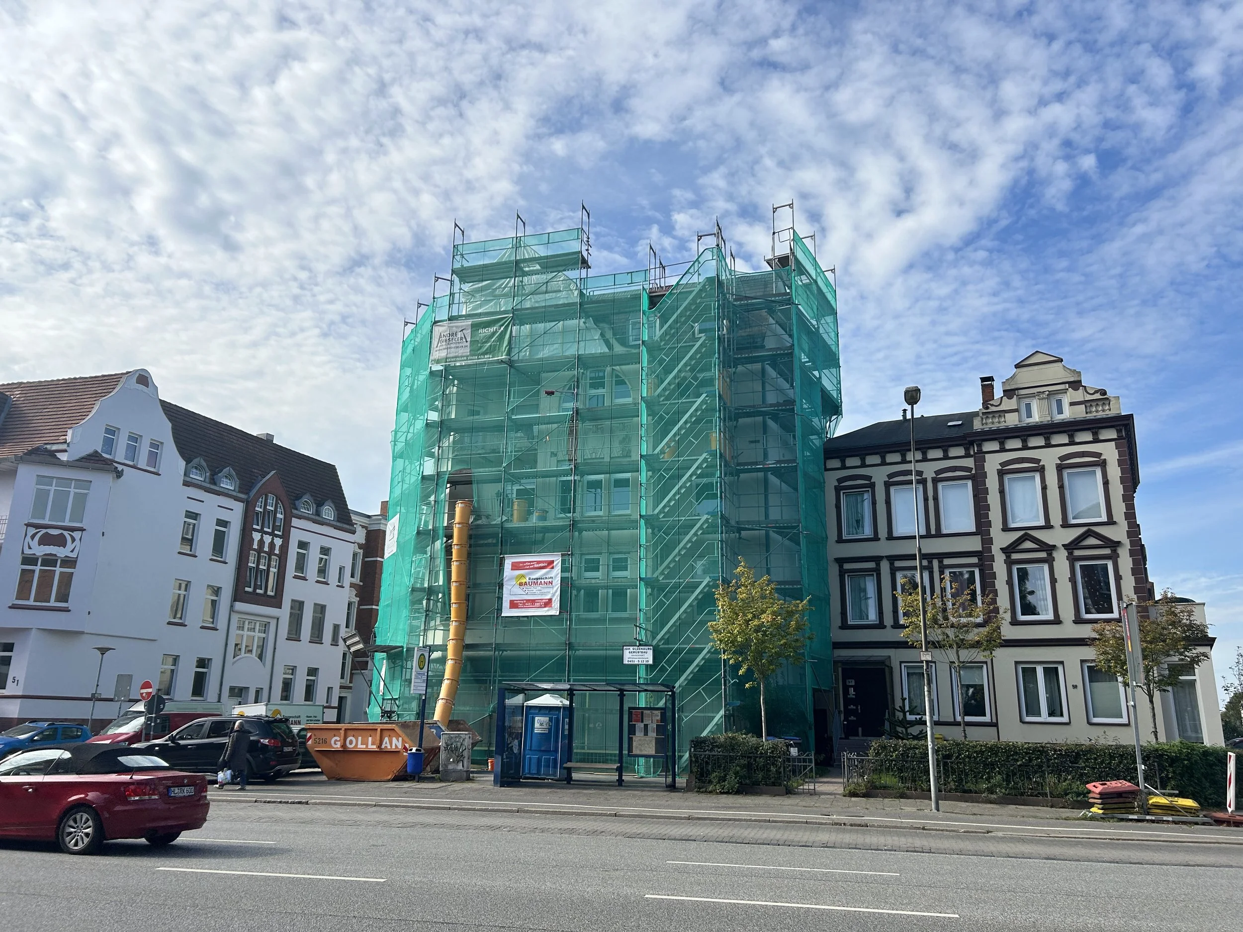 Mehrfamilienhaus von außen, komplett von Gerüst und Schutznetz umhüllt, Renovierung Außenfassade