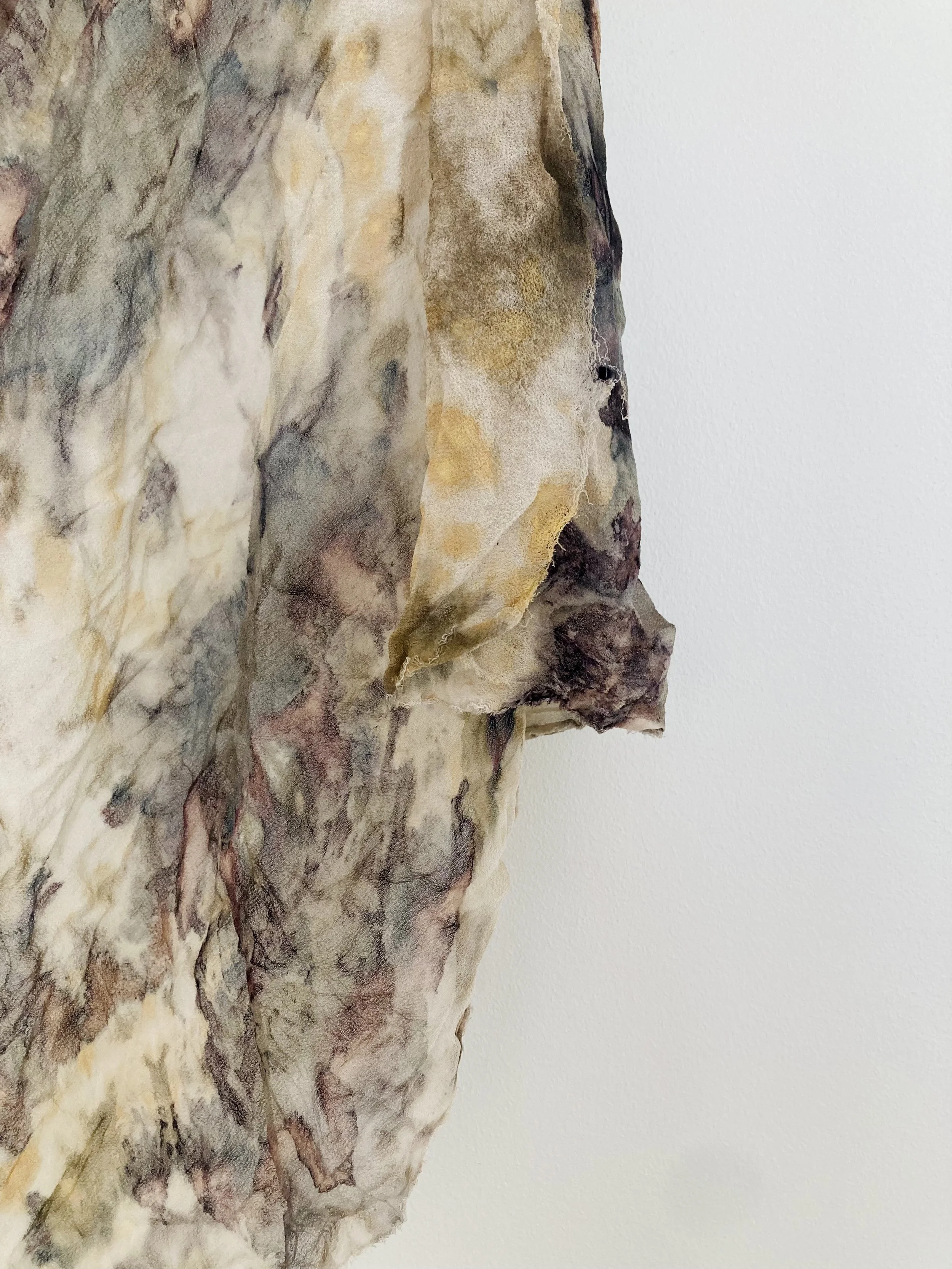 Close-up of a textured abstract artwork with various earthy tones against a plain white background.