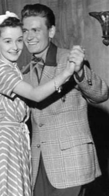 A young girl and a man dancing together, smiling, in a black and white photo.