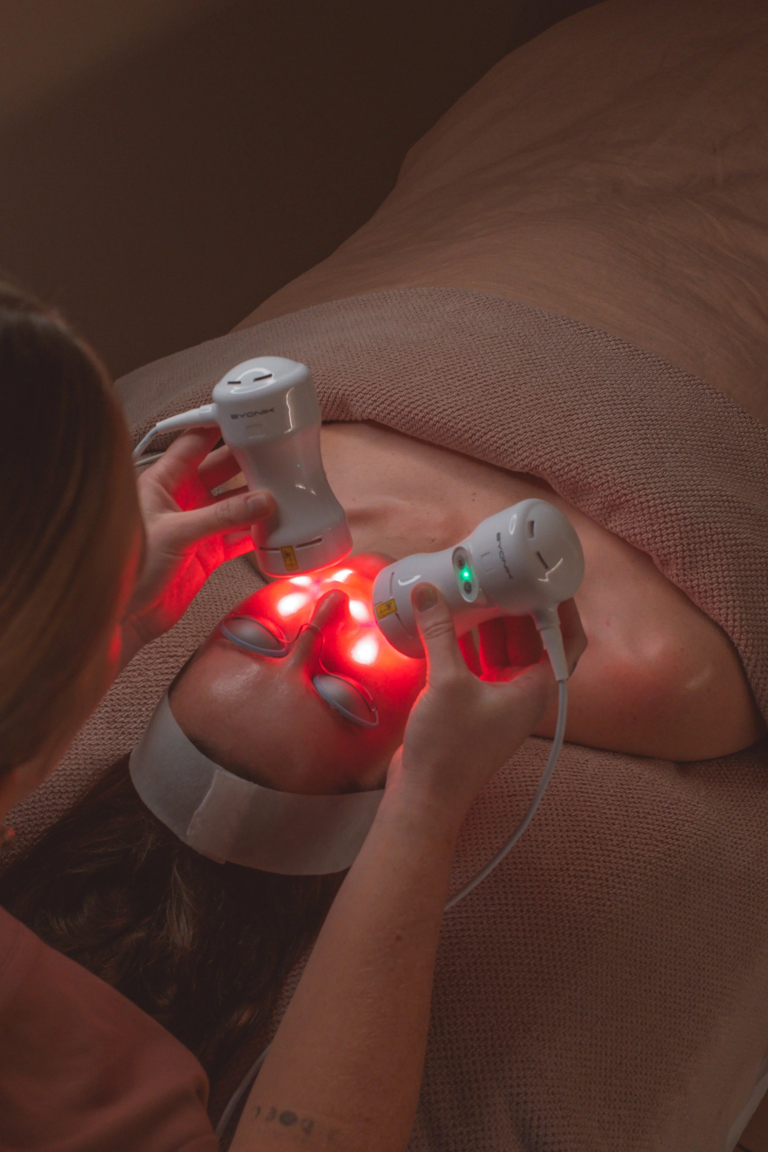 Person undergoing red light therapy treatment on face in a clinical setting.