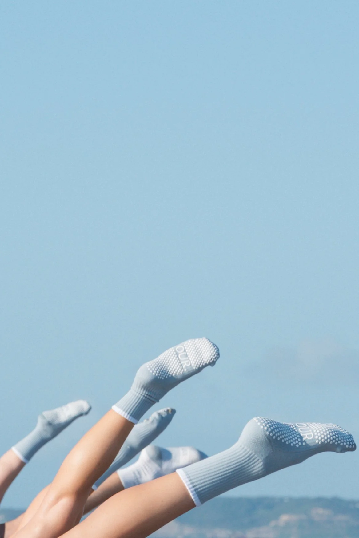 Multiple hands wearing white gloves reaching upward against a clear blue sky background.