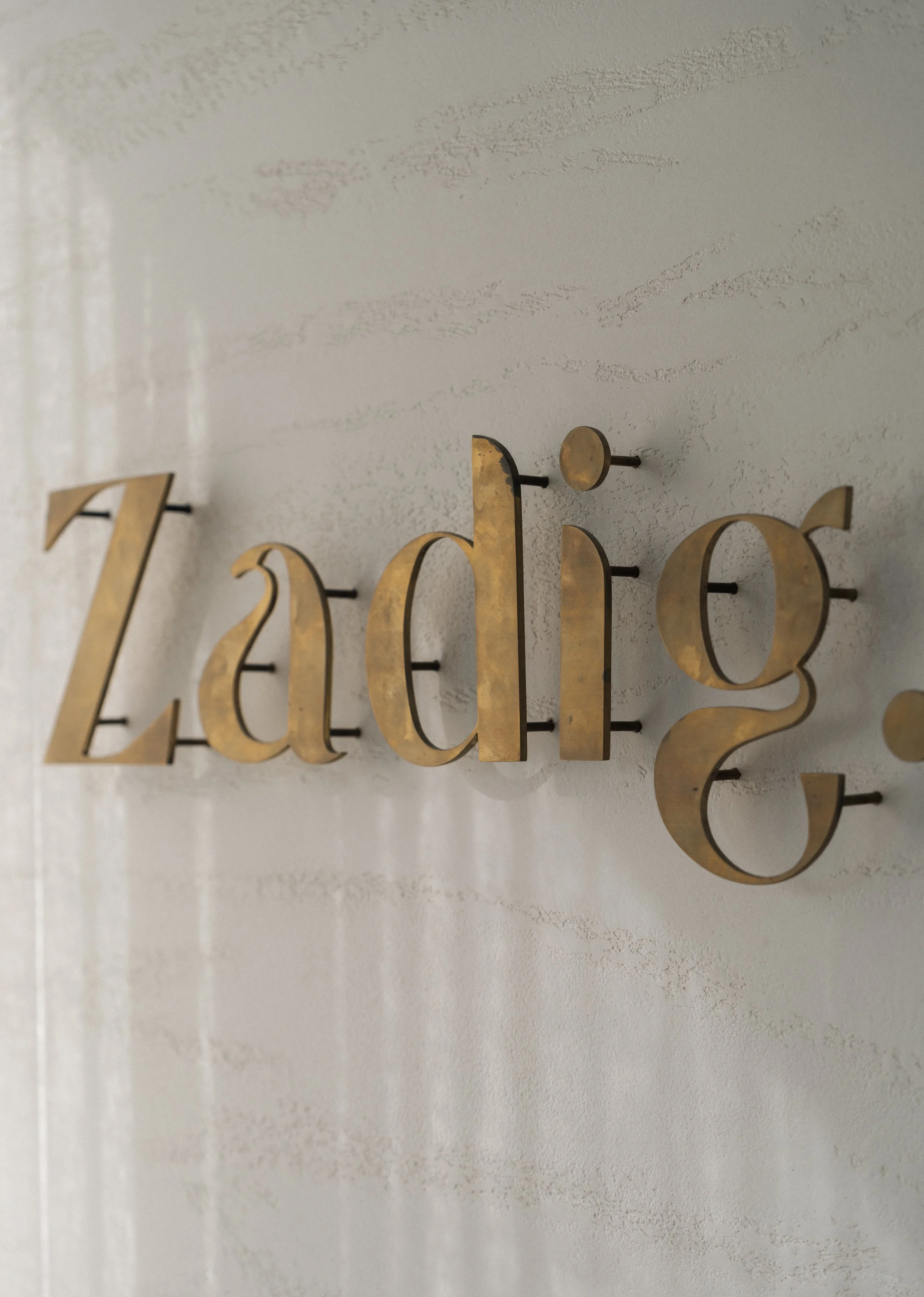 Close-up view of a decorative wall sign with metallic gold letters forming the word 'Dreams' mounted on a textured white wall.