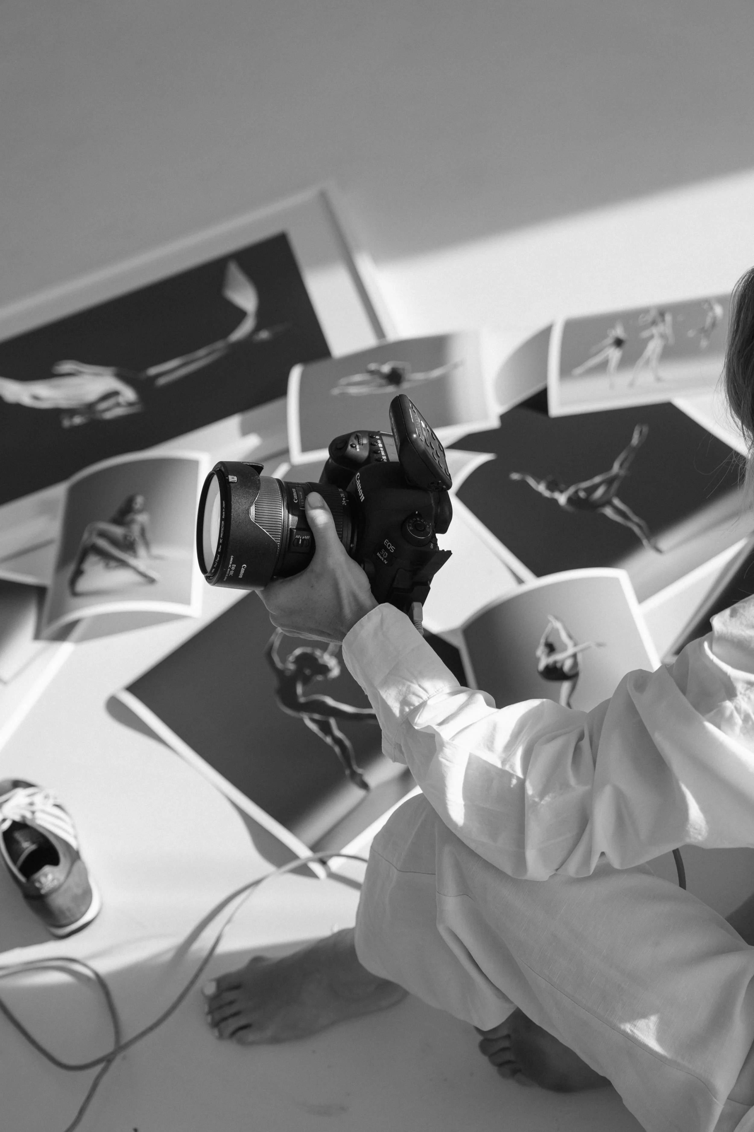 Person holding a camera and looking at photographs of a dancer in various poses.