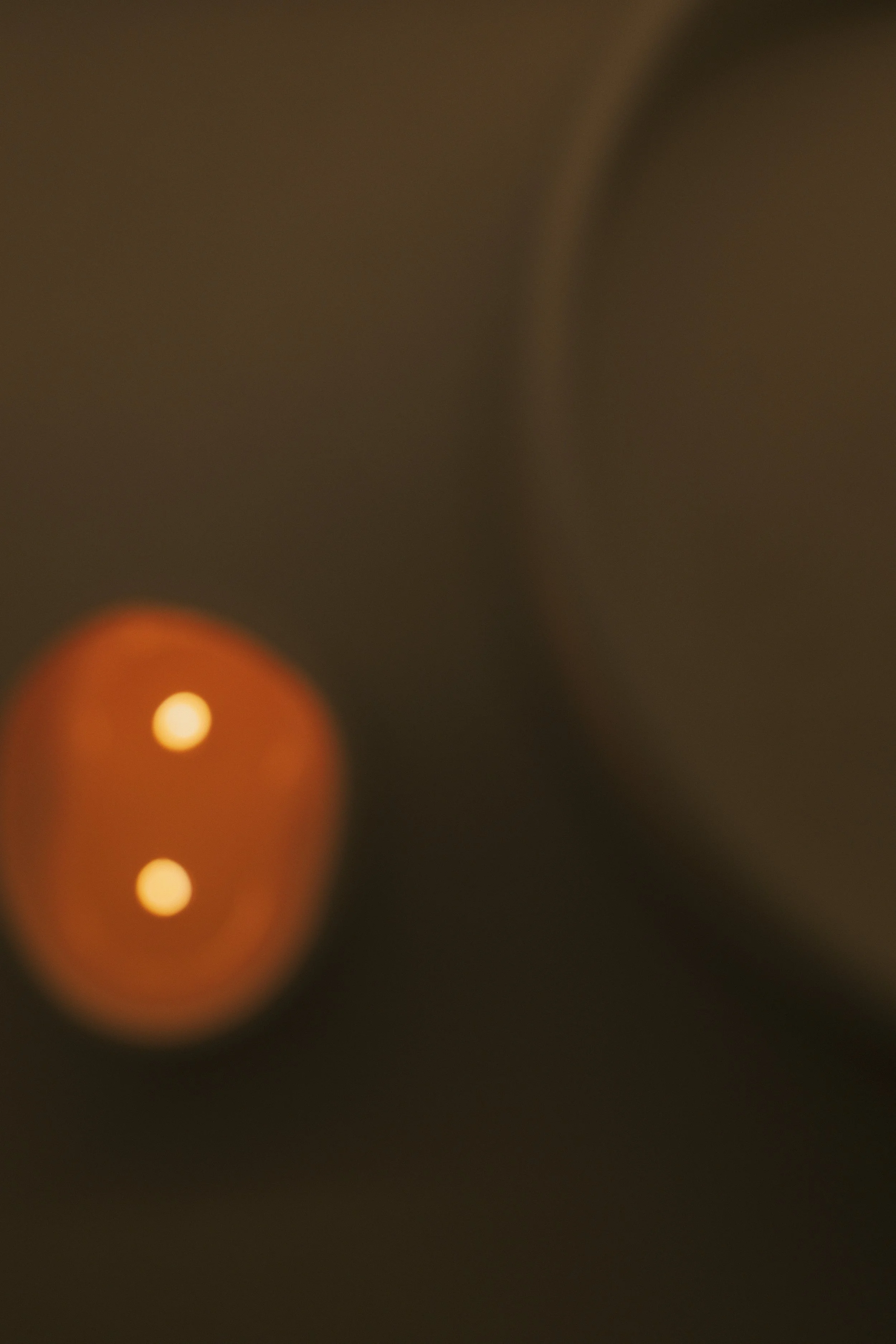 Blurred image showing warm lighting, possibly candles or lamps, with dark surroundings.