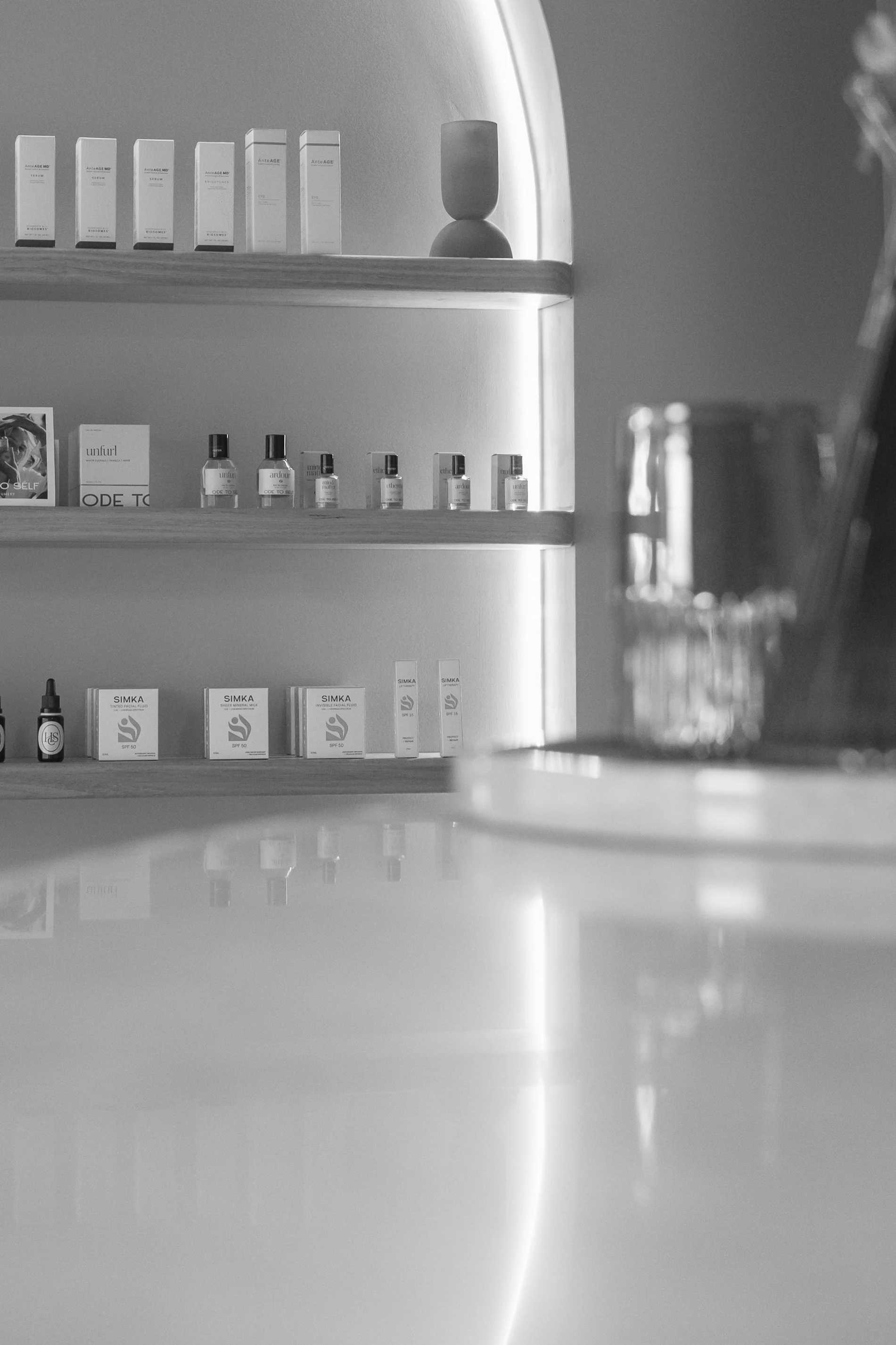 A shelf with skincare and beauty products, some boxes and bottles, in a minimalist setting with soft lighting.