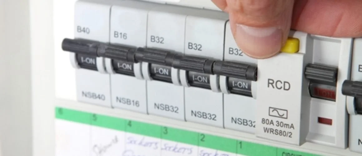 Close-up of an electrical circuit breaker panel with switches labeled B40, B16, B32, and NSB40. A hand is flipping a yellow switch.