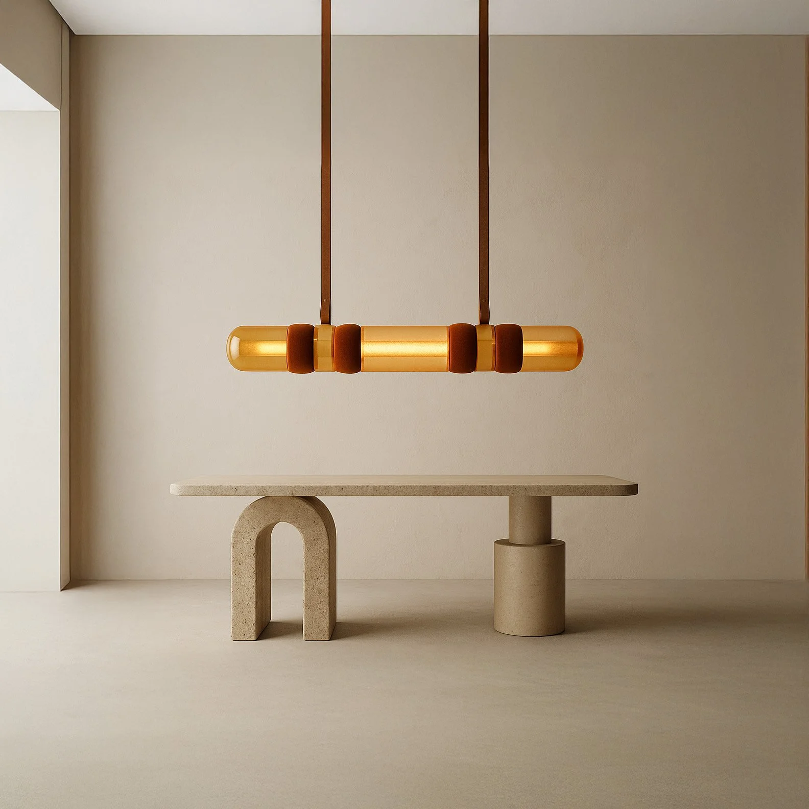 Minimalist interior featuring a beige concrete table with one sponge-shaped and one round support, and a modern hanging pendant light with a gold tube and brown accents.