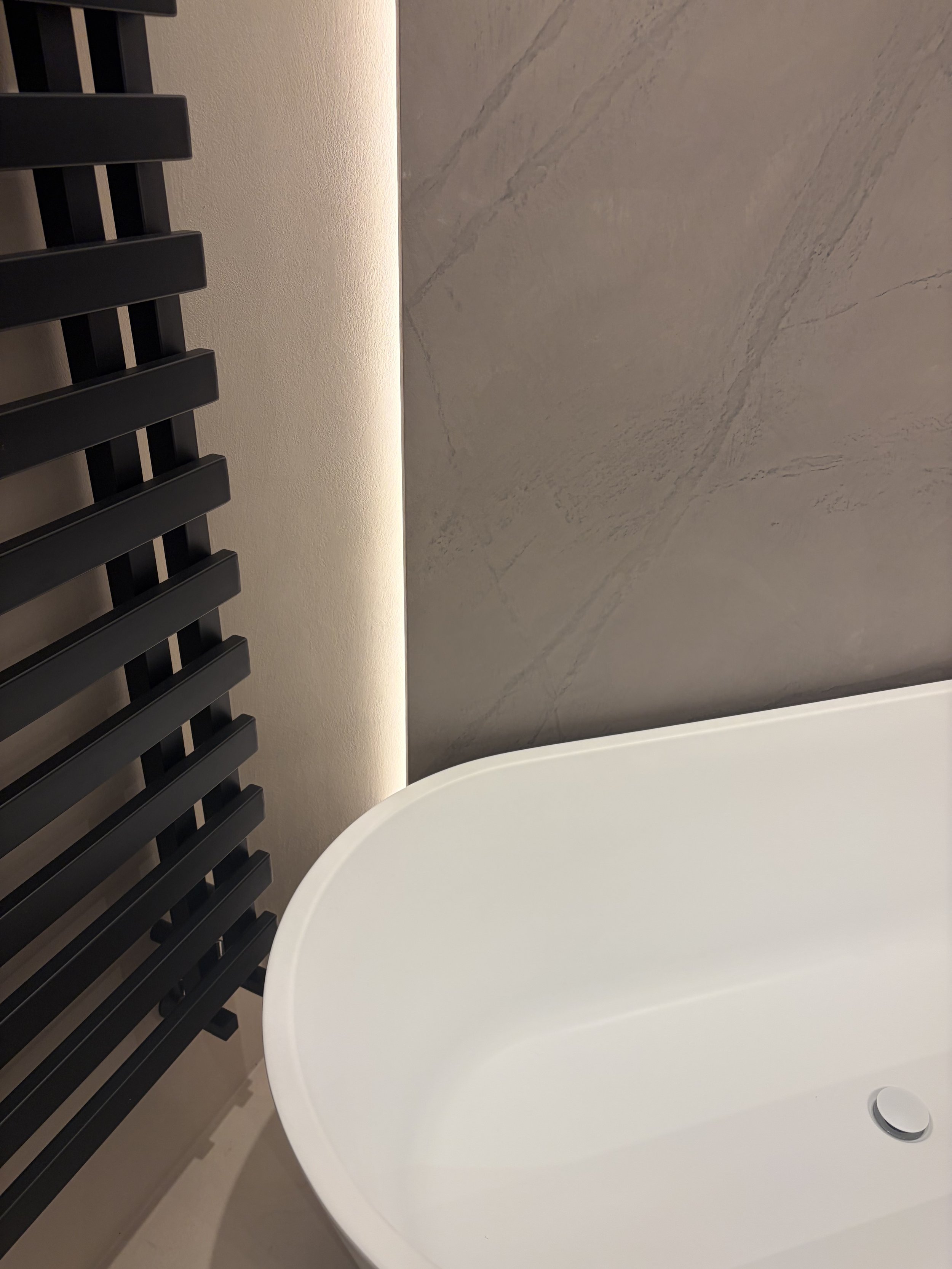 Microcement bathroom with beige walls and marble effect microcement feature wall panel