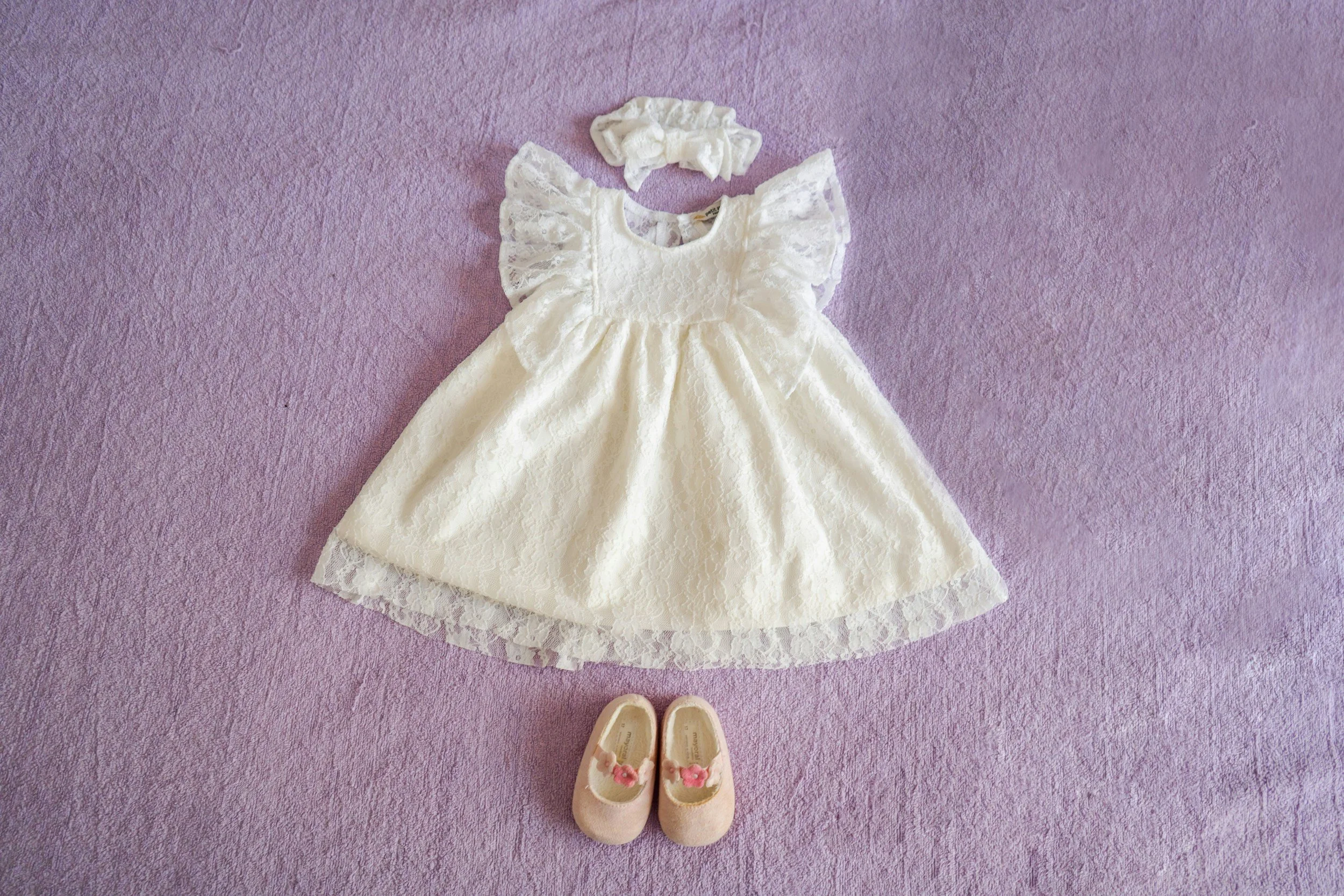 A pair of small pink baby shoes with white laces resting on a wooden surface.