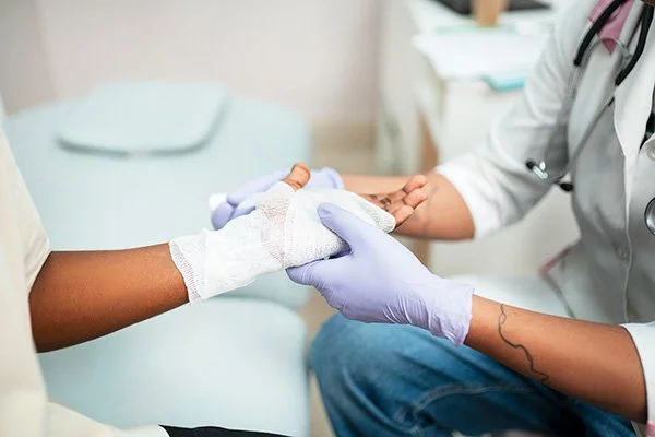 Un professionnel de la santé soignant la main d'un patient dans un environnement médical.