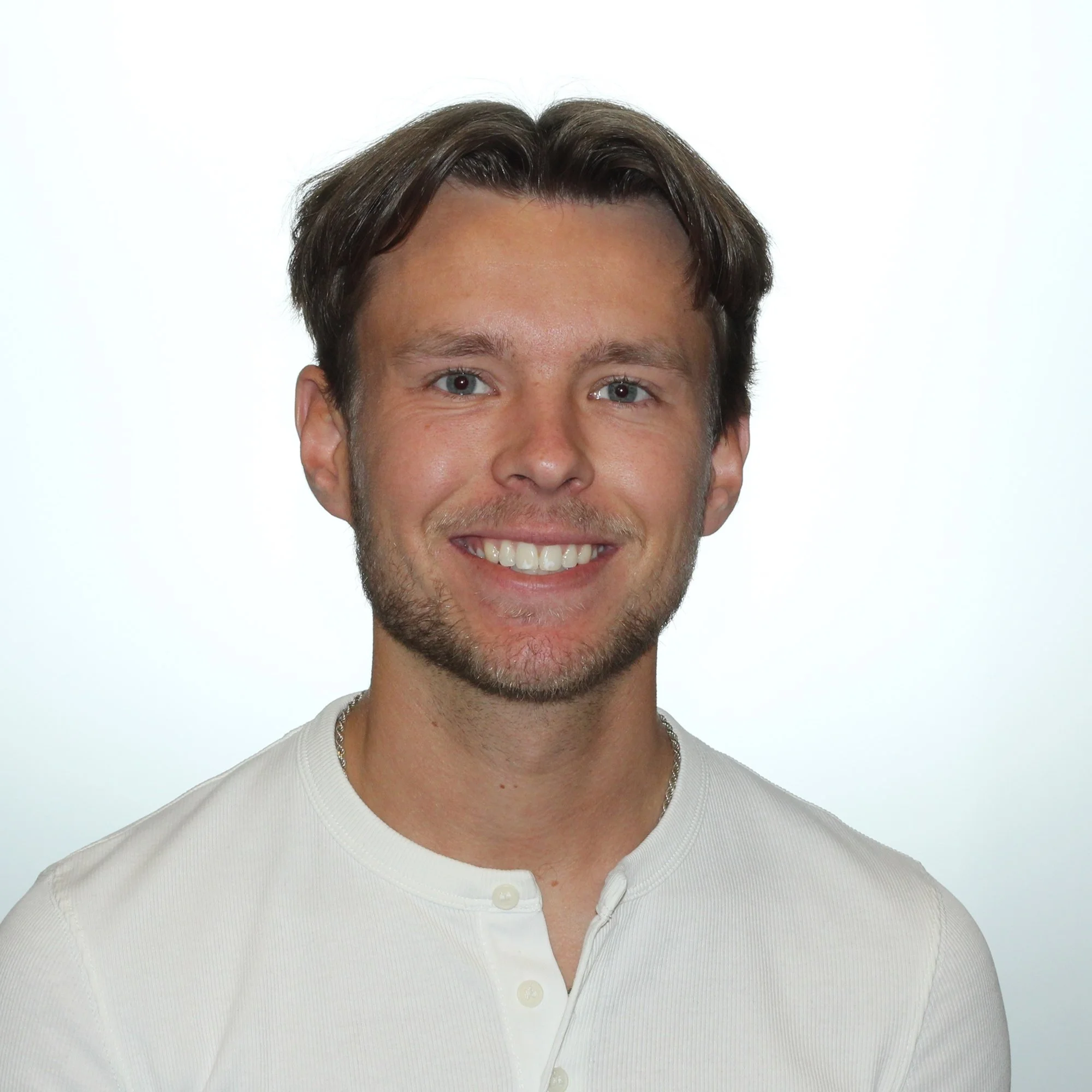 Henkilö hymyilee valkoisessa paidassa valkoisella taustalla.