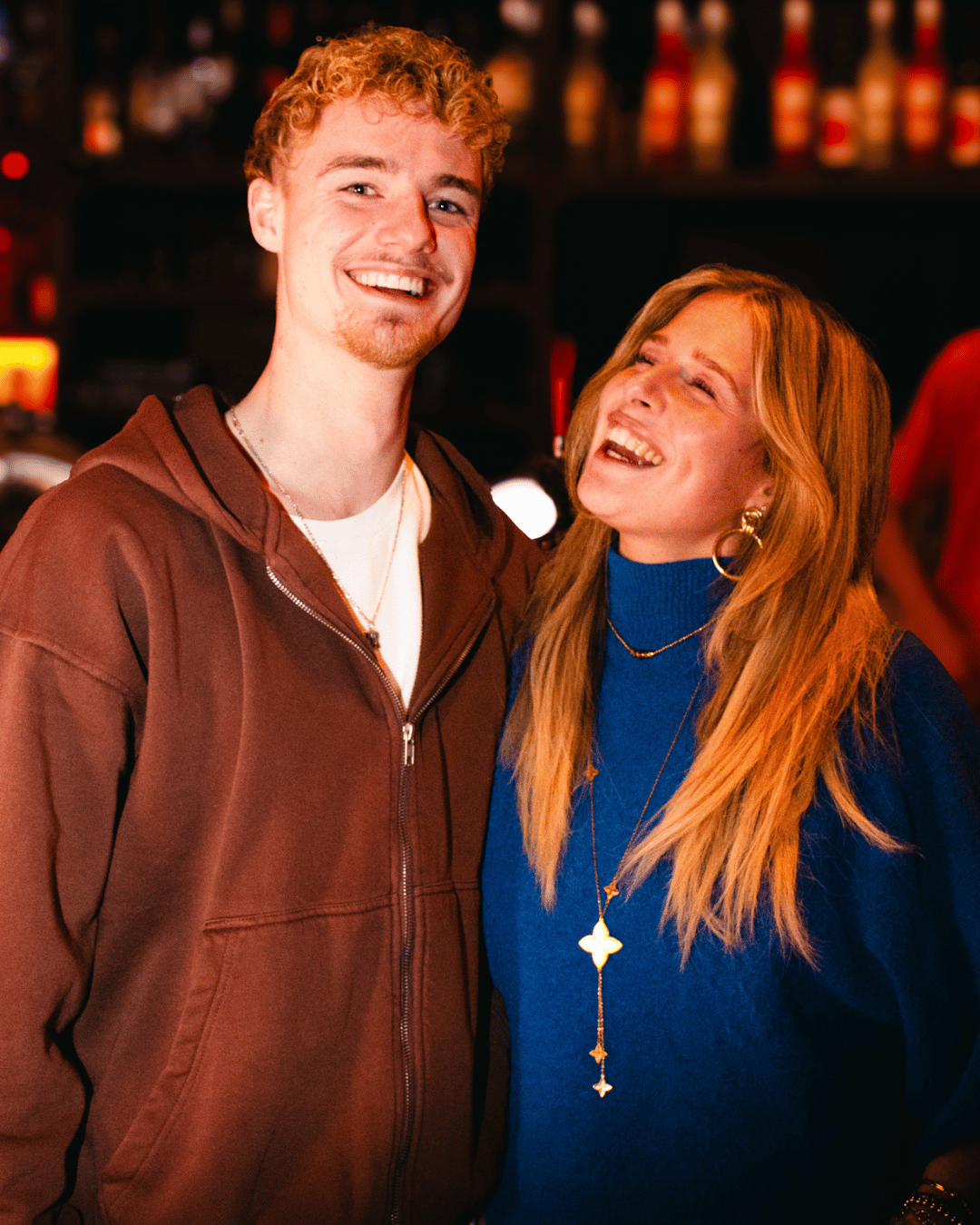 Twee mensen lachen en genieten samen in een bar of café.
