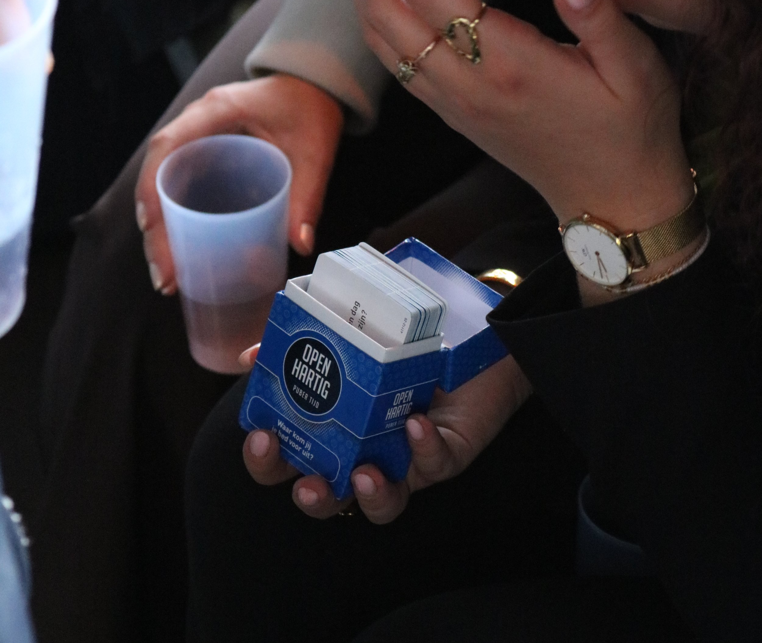 Persoon houdt een blauw pakje sigaretten en een glas met een drankje.