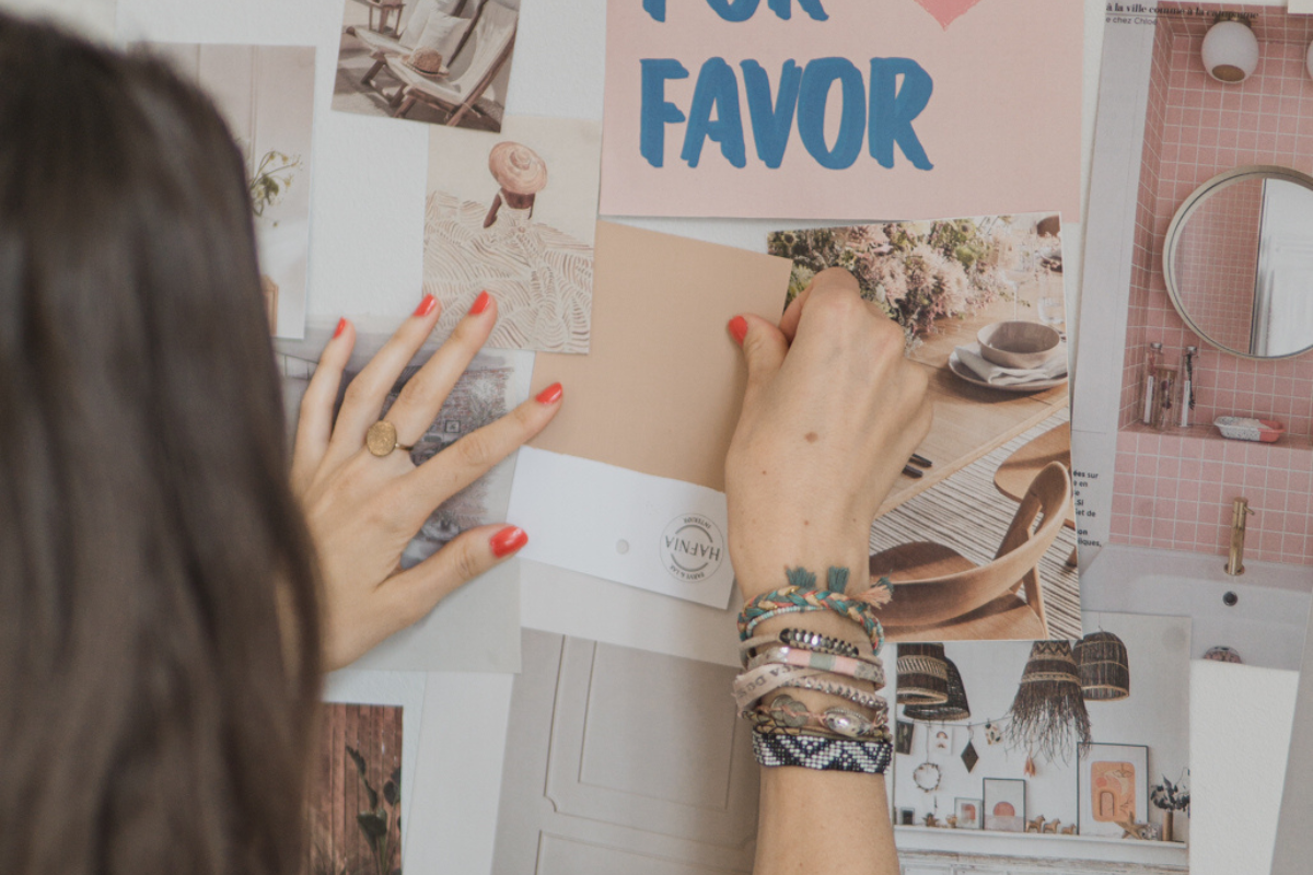 A woman creating a wall moodboard. We can see her hands