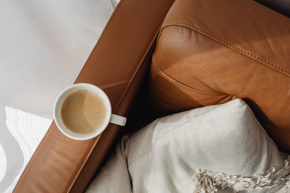 Brown leather armchair with white cushion and a cup of coffee