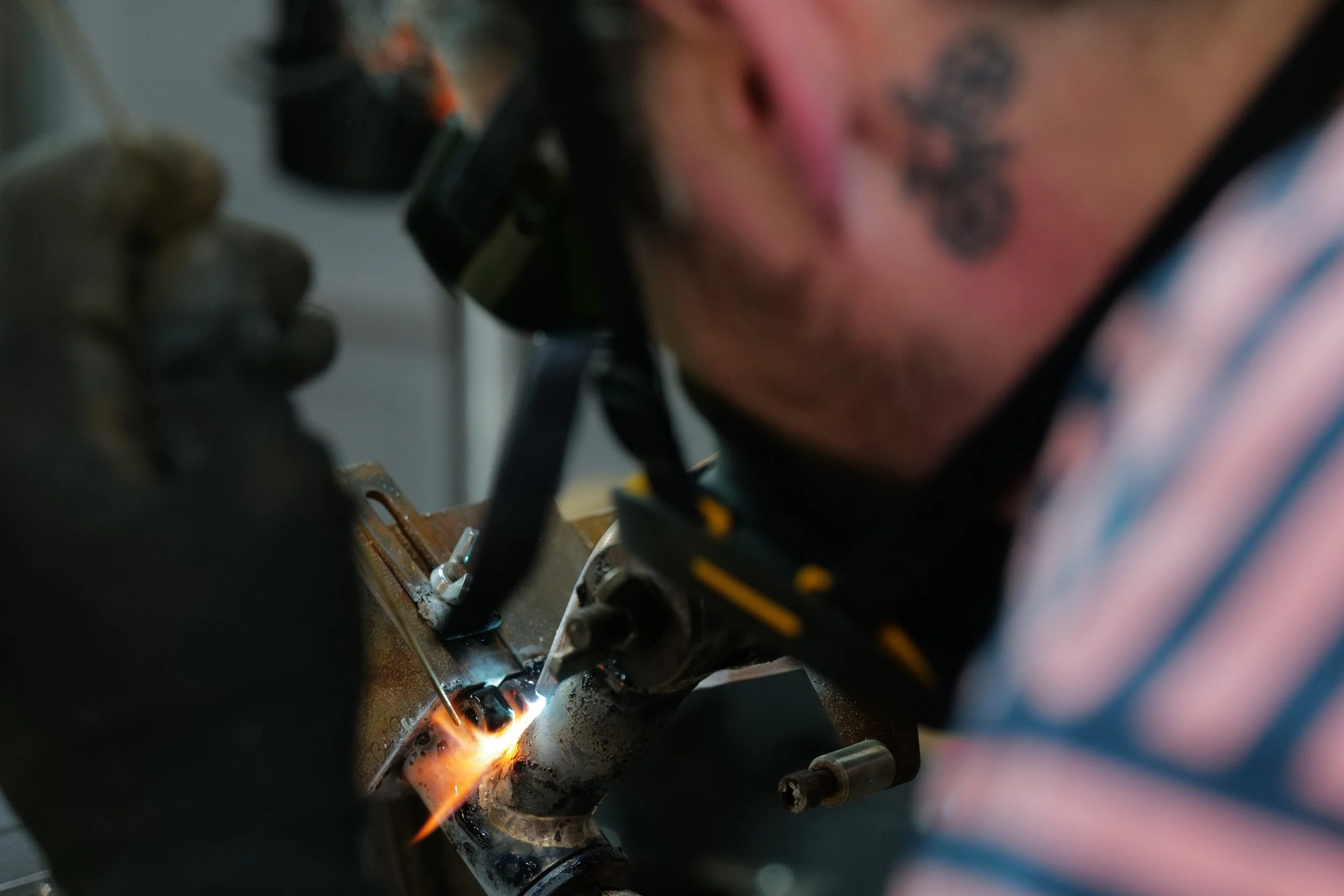  A person wearing welding goggles and gloves brazing a bicycle frame 