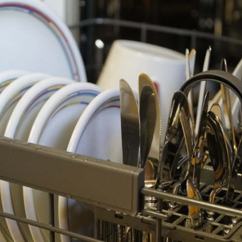Dishes and utensils in a dish rack, including plates, knives, forks, and spoons. Norwich Plumbing and Heating Ltd.