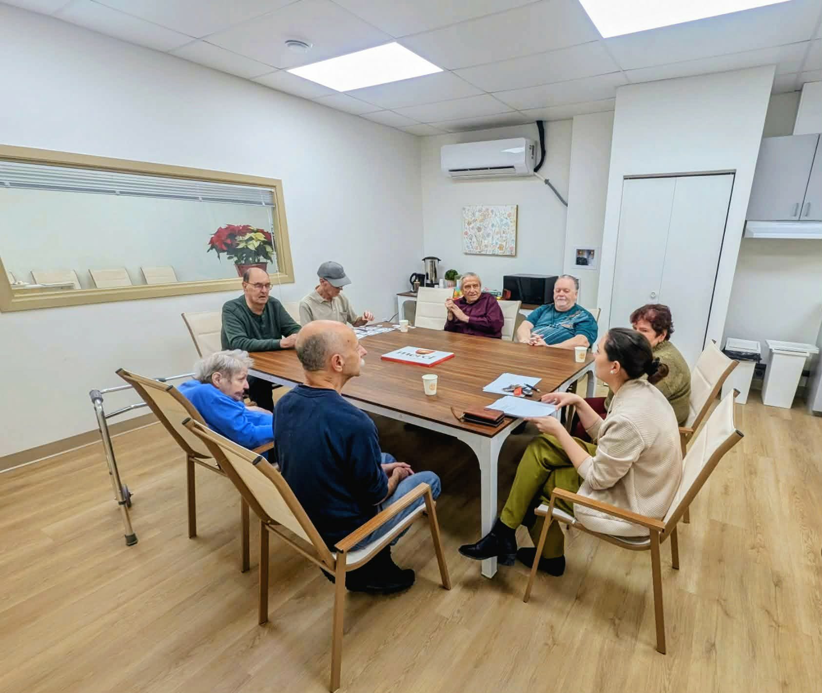 groupe de personnes âgées et une jeune femme dans un salon en train de boire du café
