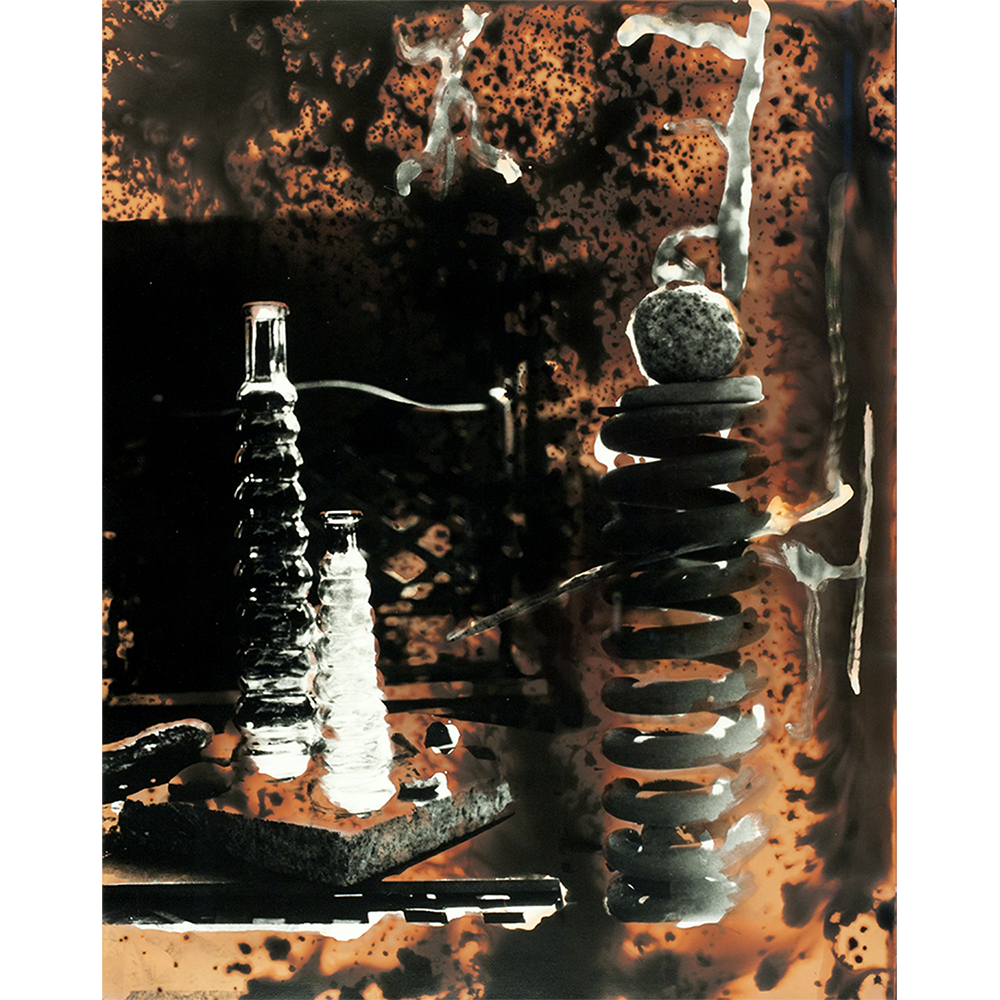 Orange colored chemigram hand-printed photograph of objects on patio table.