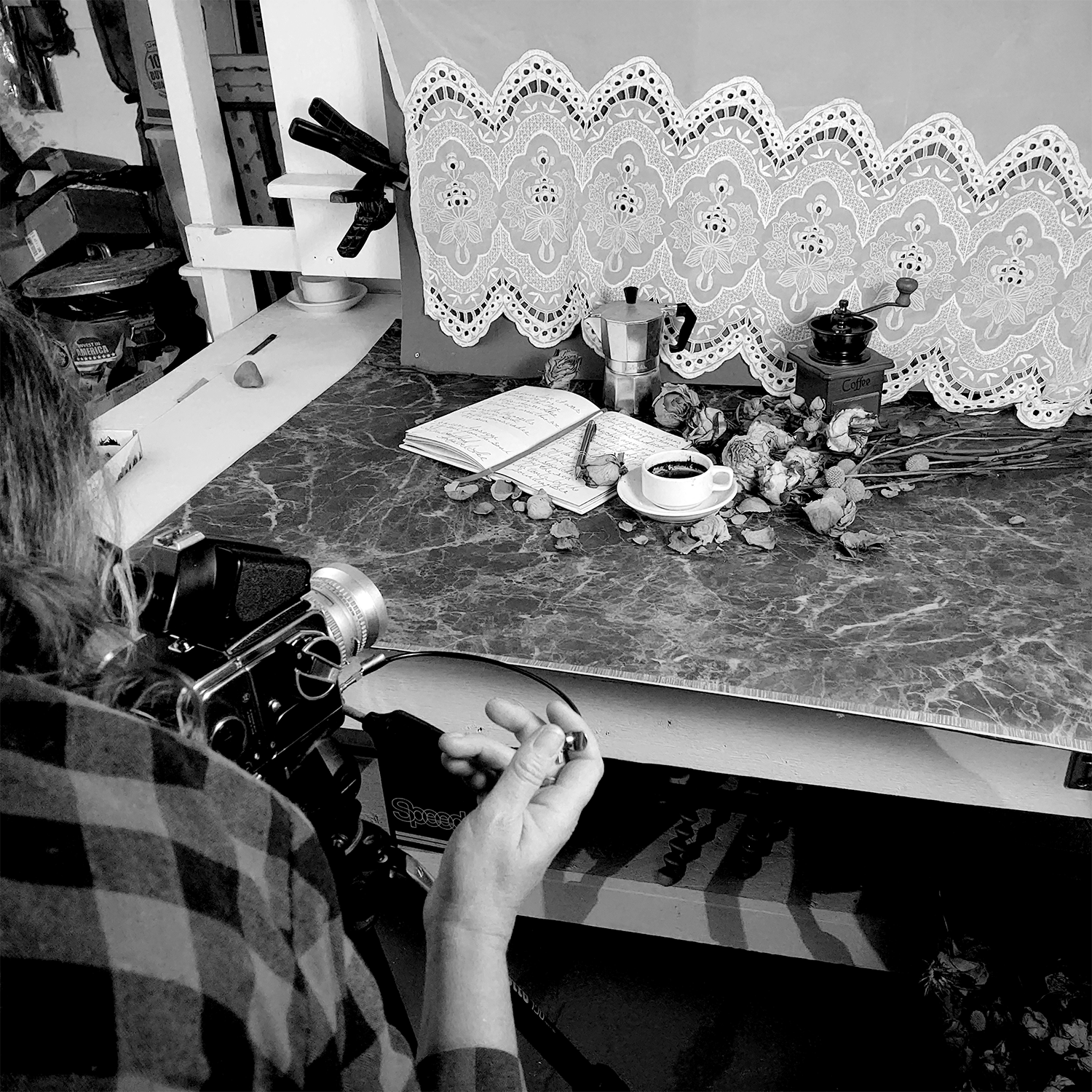 Photographic artist, Colleen Graham, behind a medium format camera photographing still life on set.