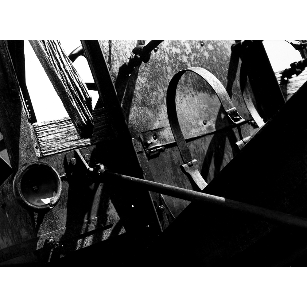 Black-and-white photograph of antique and rusted road grater, hand-printed.