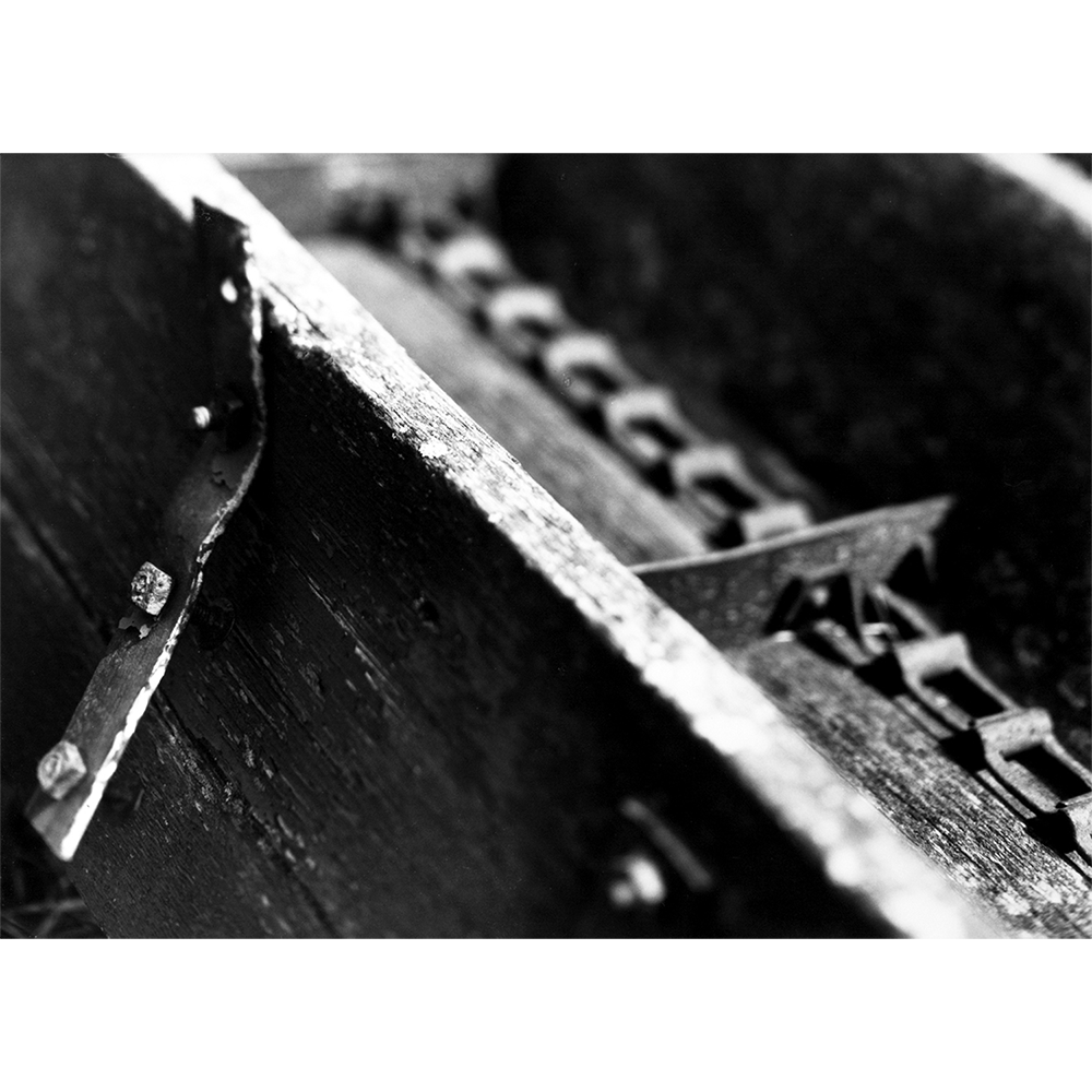 Black-and-white photograph of antique farming conveyor, hand-printed.