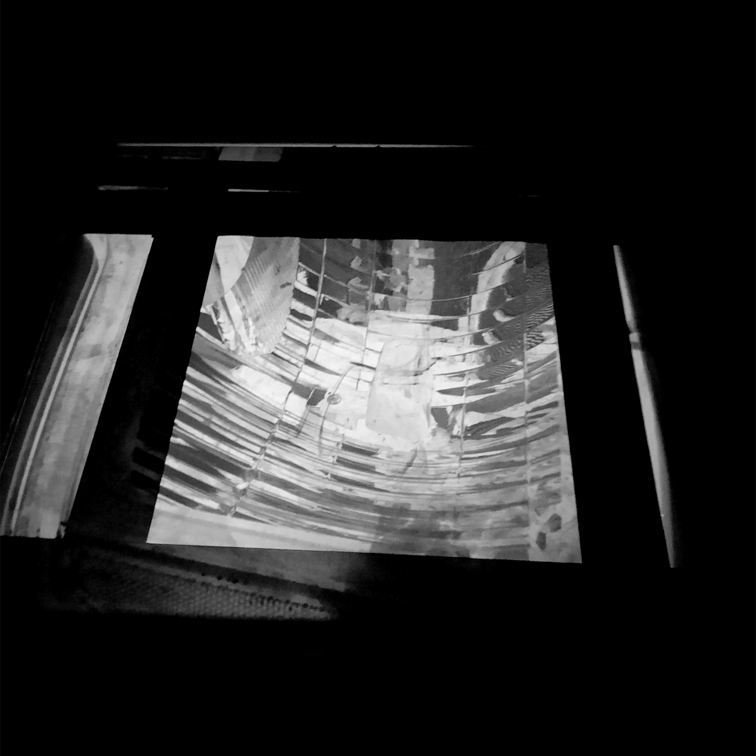 Negative projected onto photographic paper in darkroom easel.