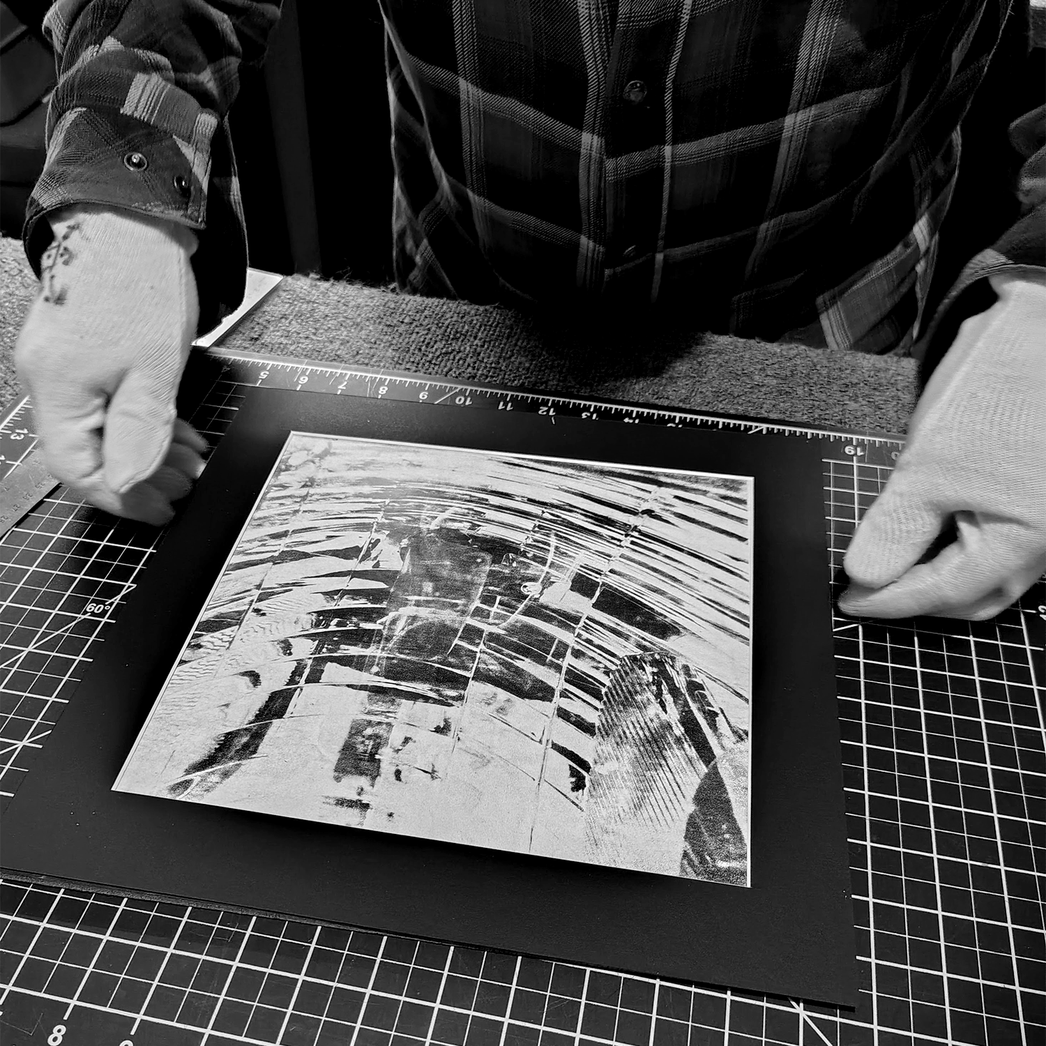 Shannon Graham placing mat on photograph with gloved hands.