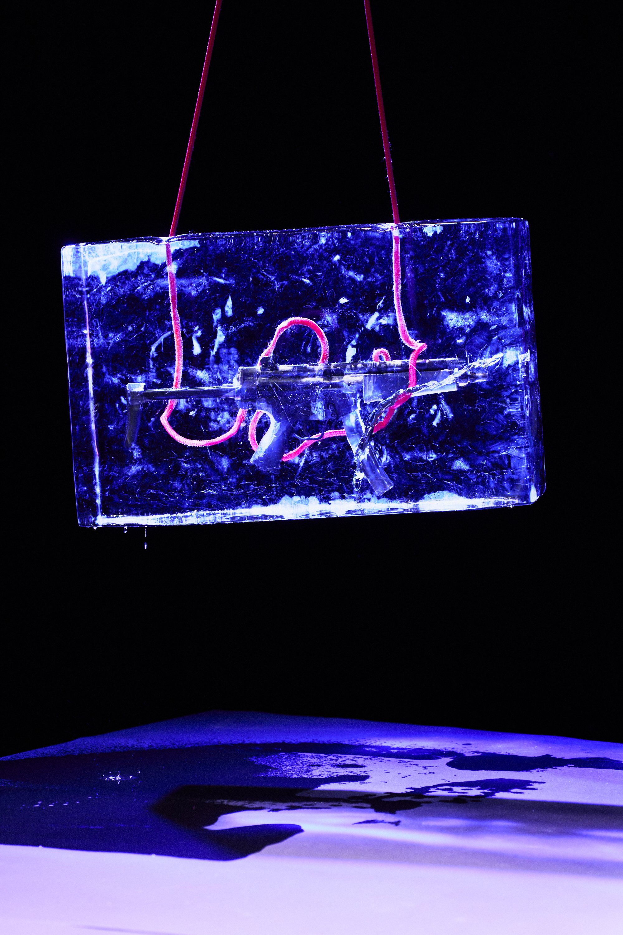 Ein beleuchteter, schwebender Kristallblock mit roten elektrischen Drähten darin, vor einem schwarzen Hintergrund.