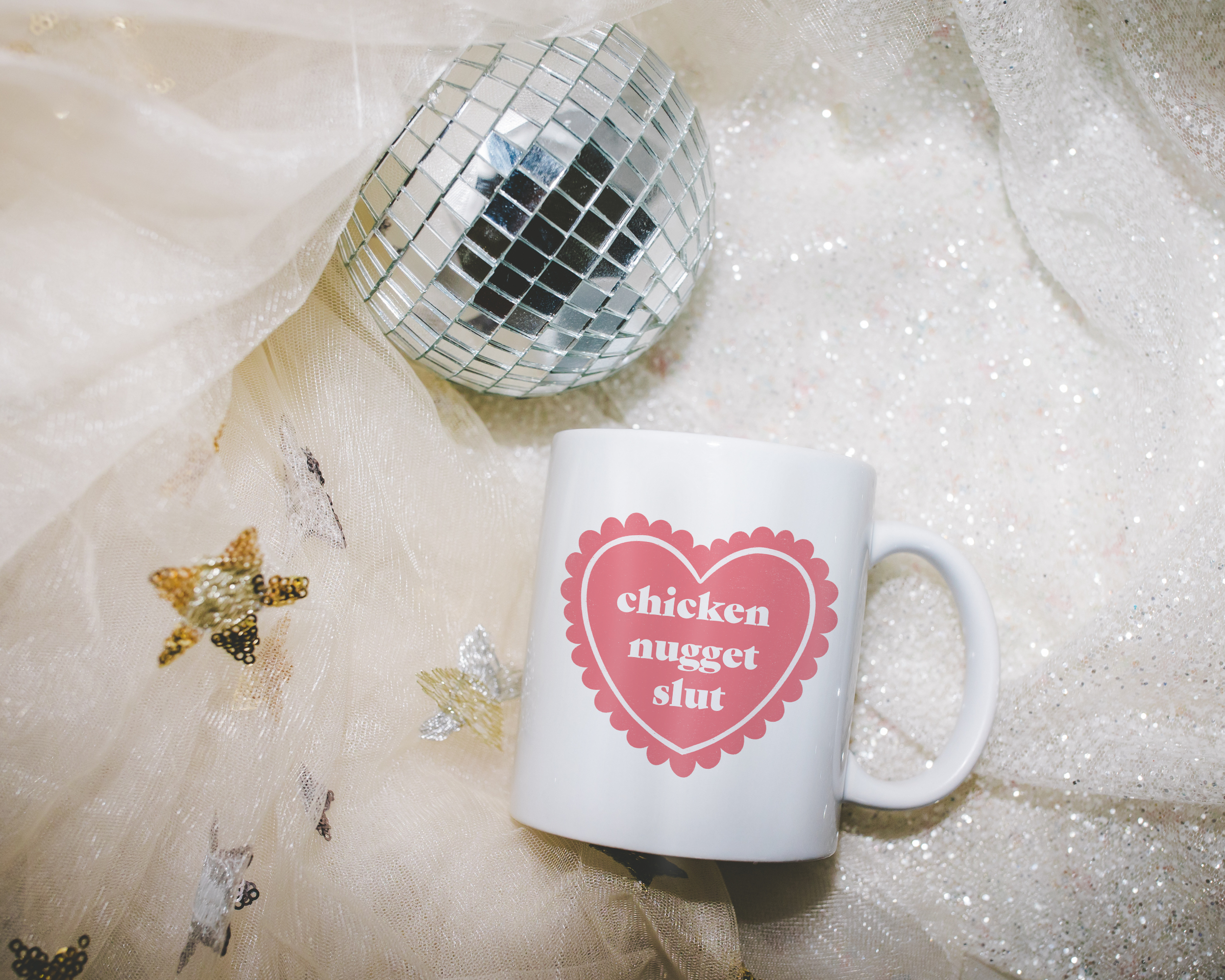 Sassy dopamine decor White coffee mug that says "chicken nugget slut" in a retro vintage style frilly heart that's pink with a retro font.. Available in 11oz and 15oz