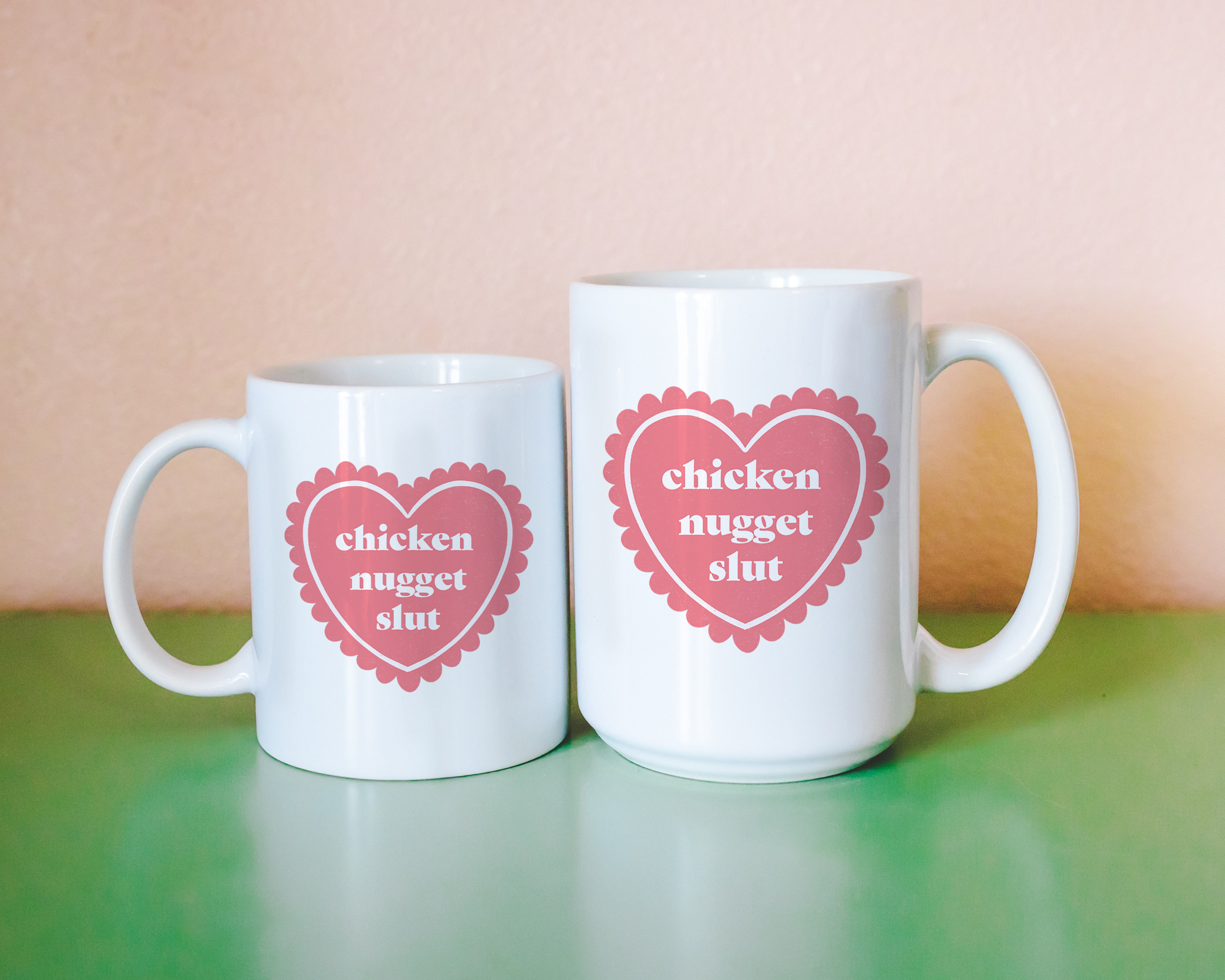 Sassy dopamine decor White coffee mug that says "chicken nugget slut" in a retro vintage style frilly heart that's pink with a retro font.. Available in 11oz and 15oz
