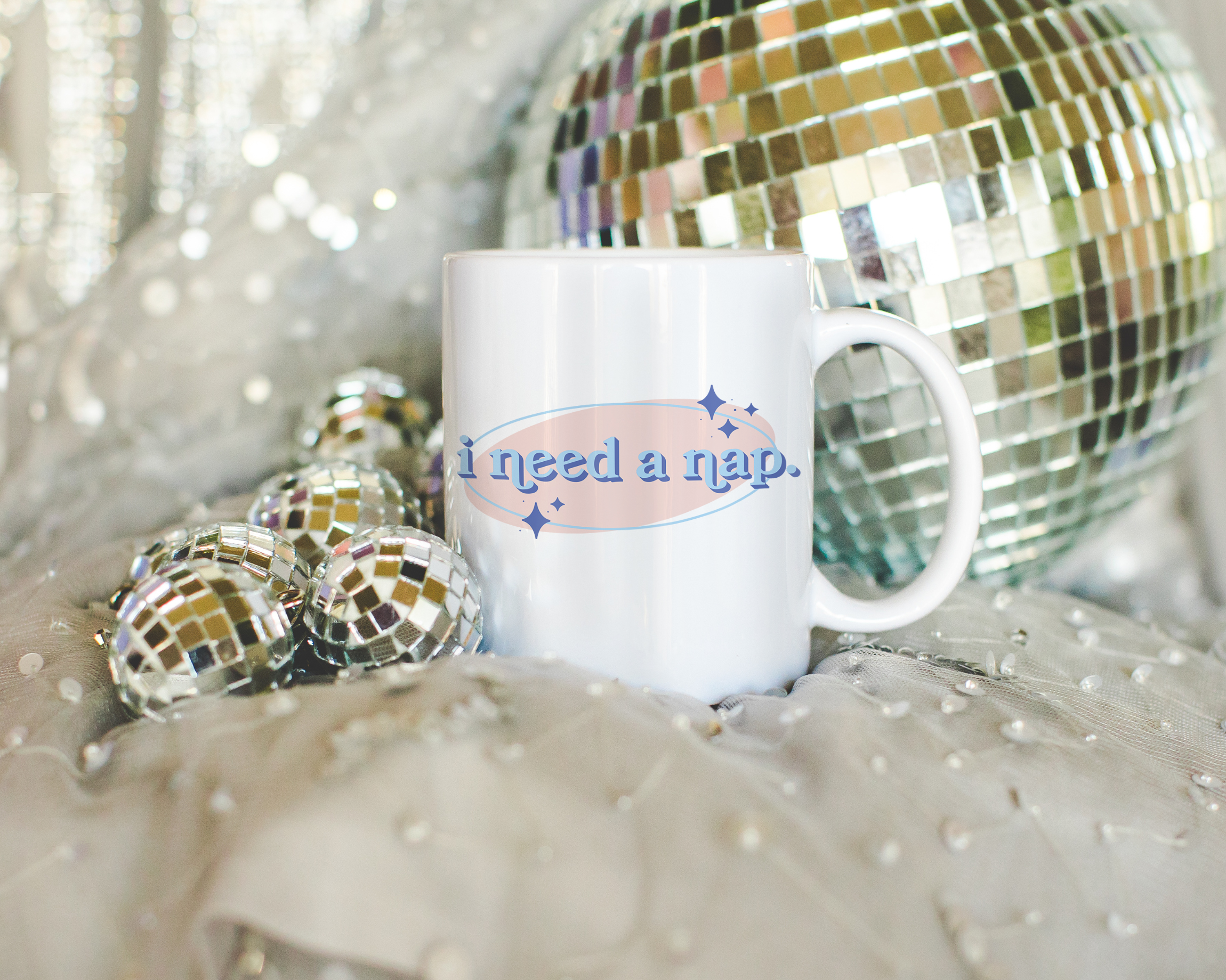 White coffee mug that says "I need a nap" in a retro vintage font that's blue and pink. Available in 11oz and 15oz