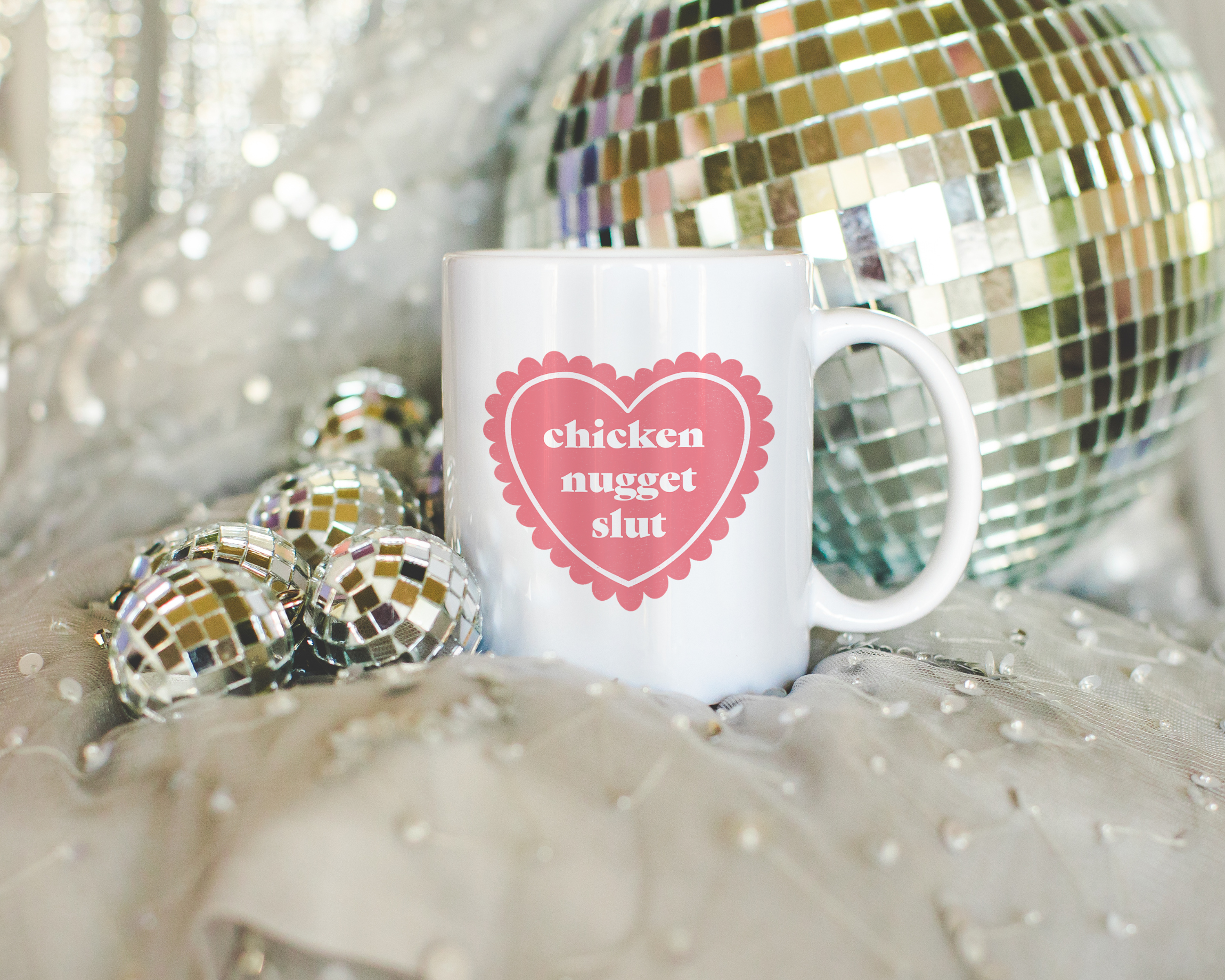 Sassy dopamine decor White coffee mug that says "chicken nugget slut" in a retro vintage style frilly heart that's pink with a retro font.. Available in 11oz and 15oz