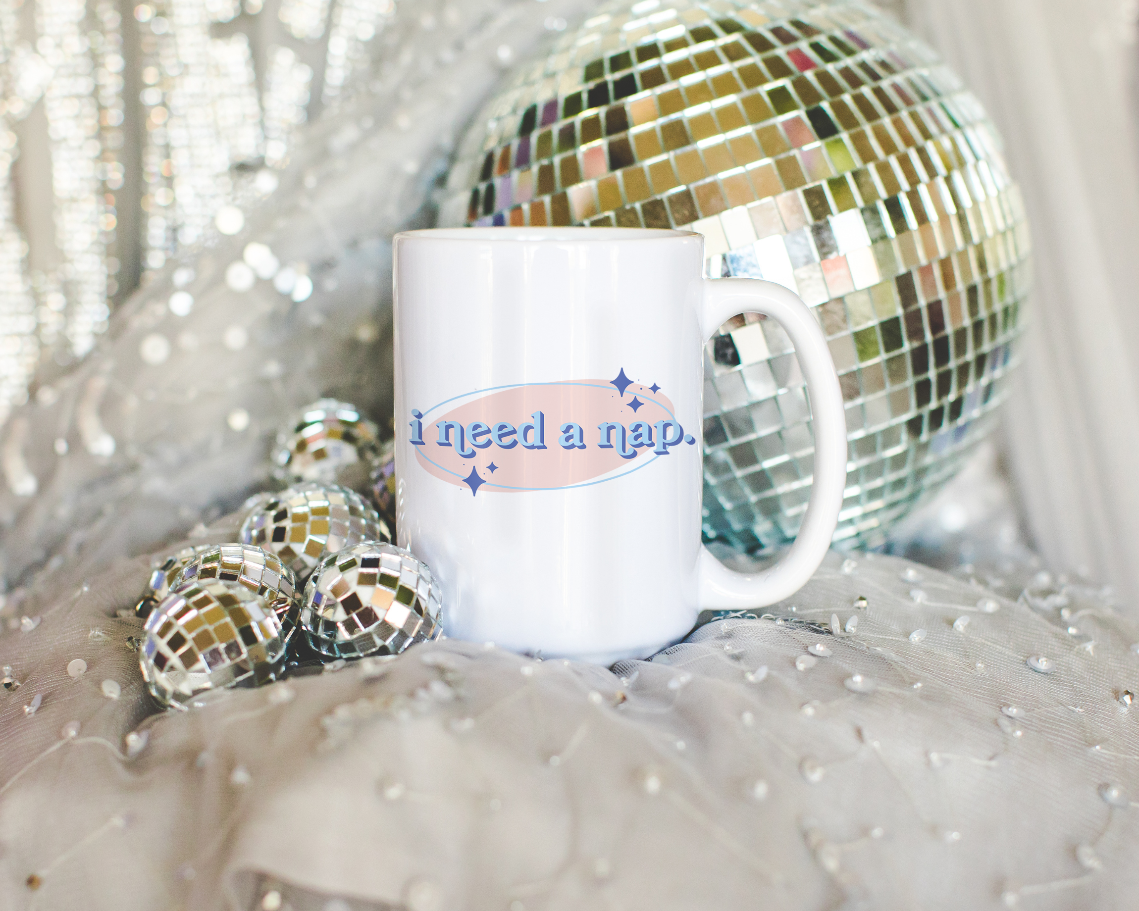 White coffee mug that says "I need a nap" in a retro vintage font that's blue and pink. Available in 11oz and 15oz