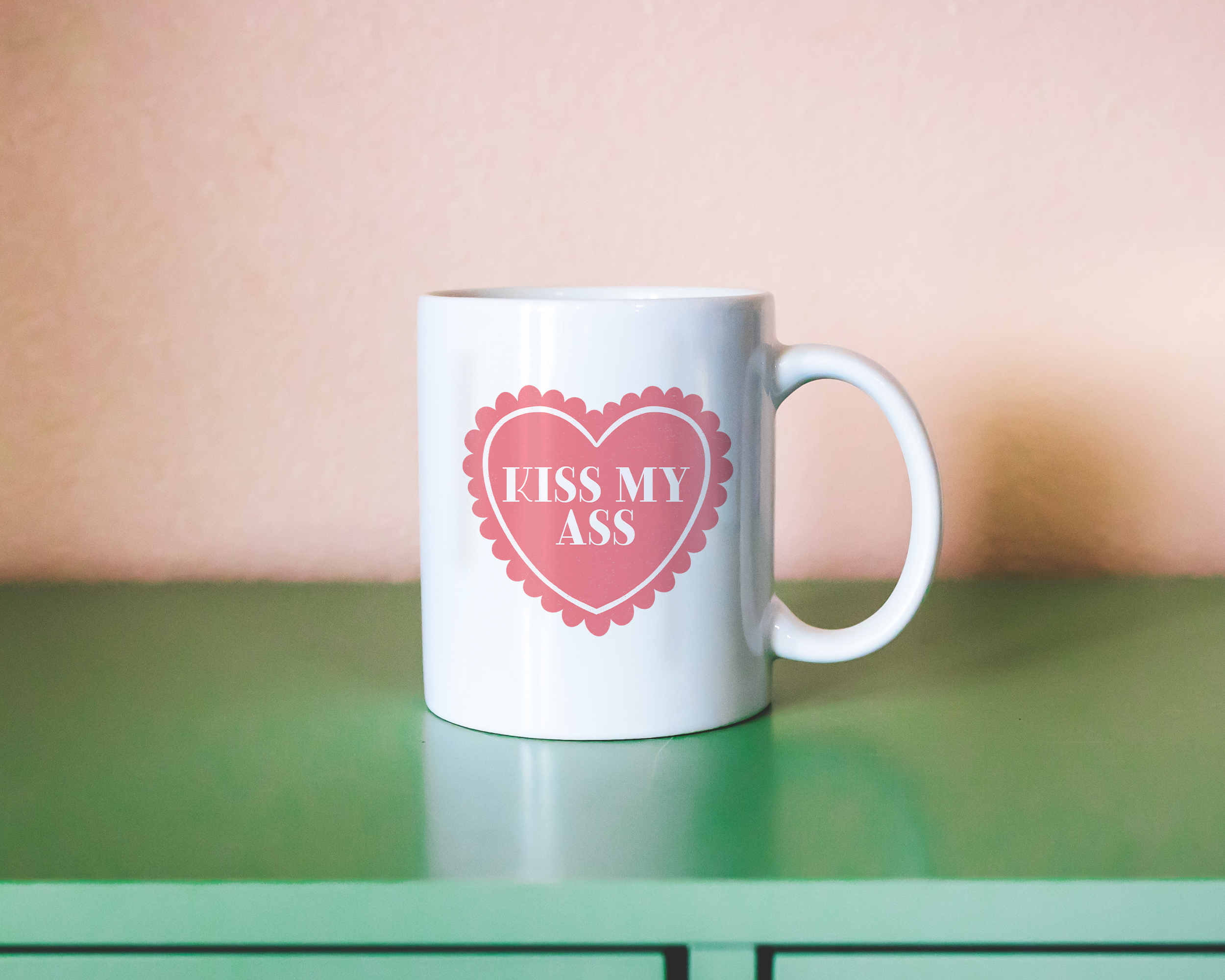 Sassy dopamine decor White coffee mug that says "kiss my ass" in a retro vintage style frilly heart that's pink with a retro font.. Available in 11oz and 15oz