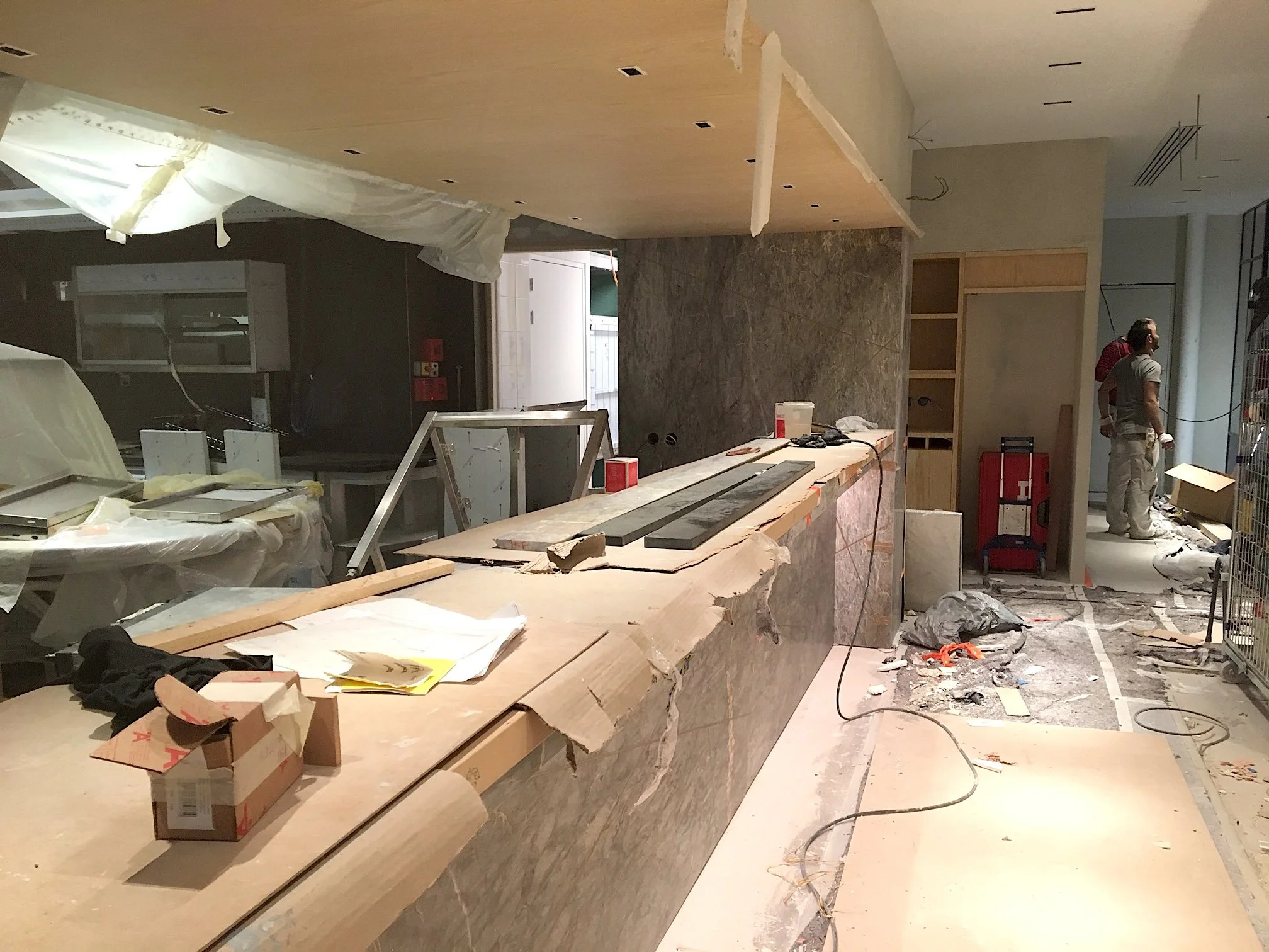 Rénovation intérieure d'un espace commercial en cours avec des matériaux de construction, des outils, et des ouvriers.