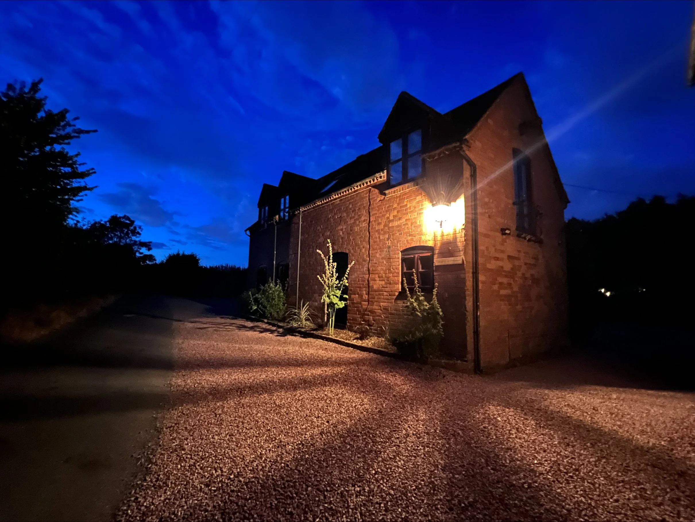 A brick house illuminated by a streetlight at night against a dark blue sky with some clouds.