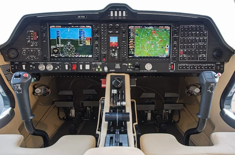 Photo of an aircraft cockpit with dual digital displays and various controls.